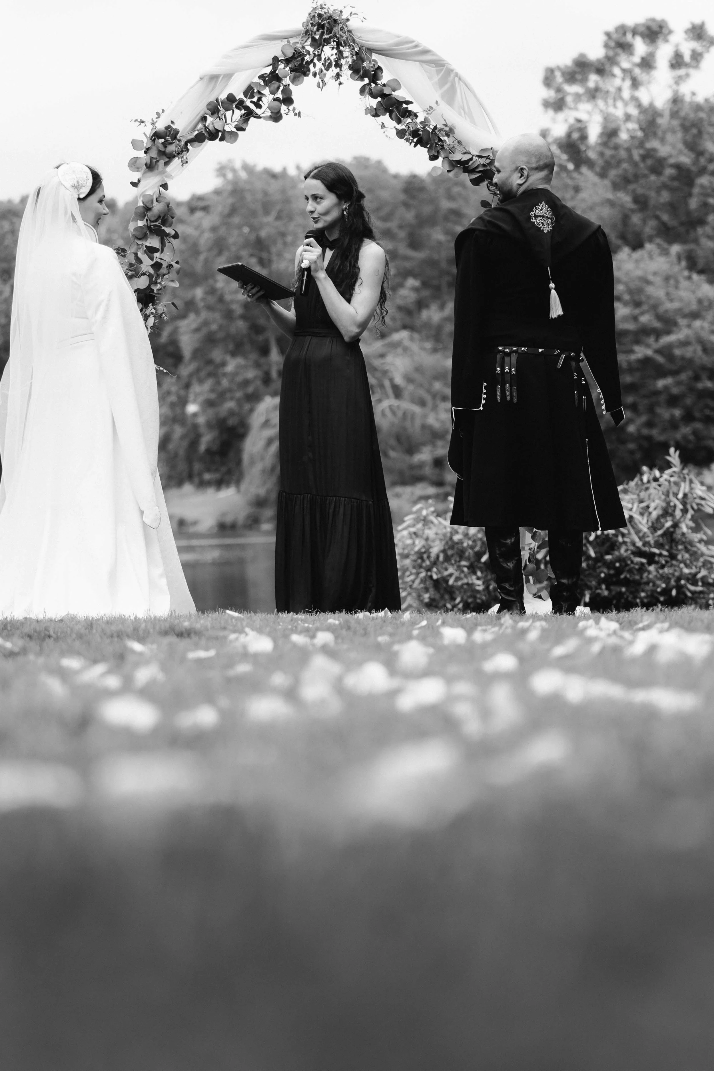 Vows exchanged outdoors with mountains behind, timeless black and white moment captured by Caz Isaiah