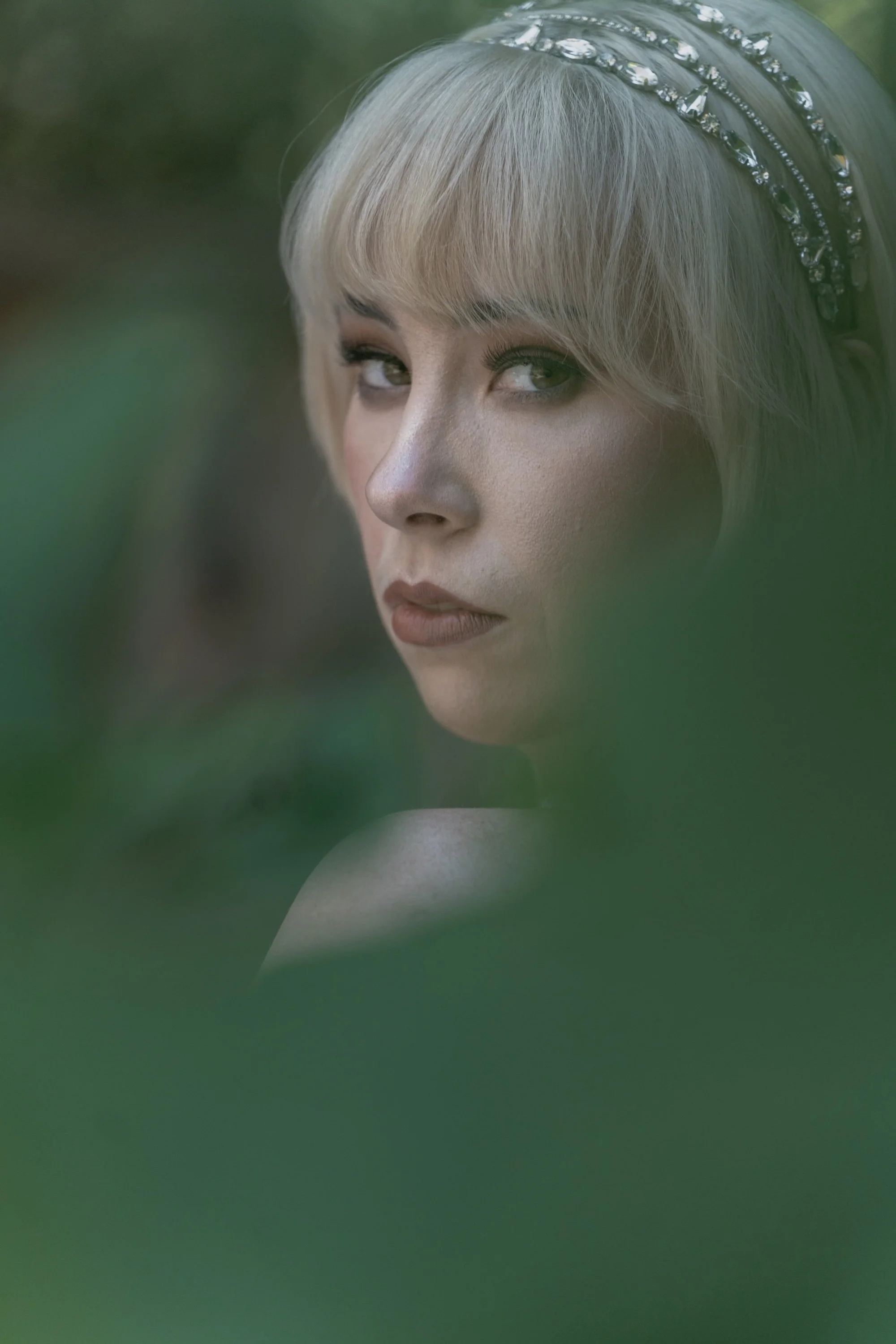 Portrait of a bride gazing through leaves, cinematic storytelling captured by Caz Isaiah.