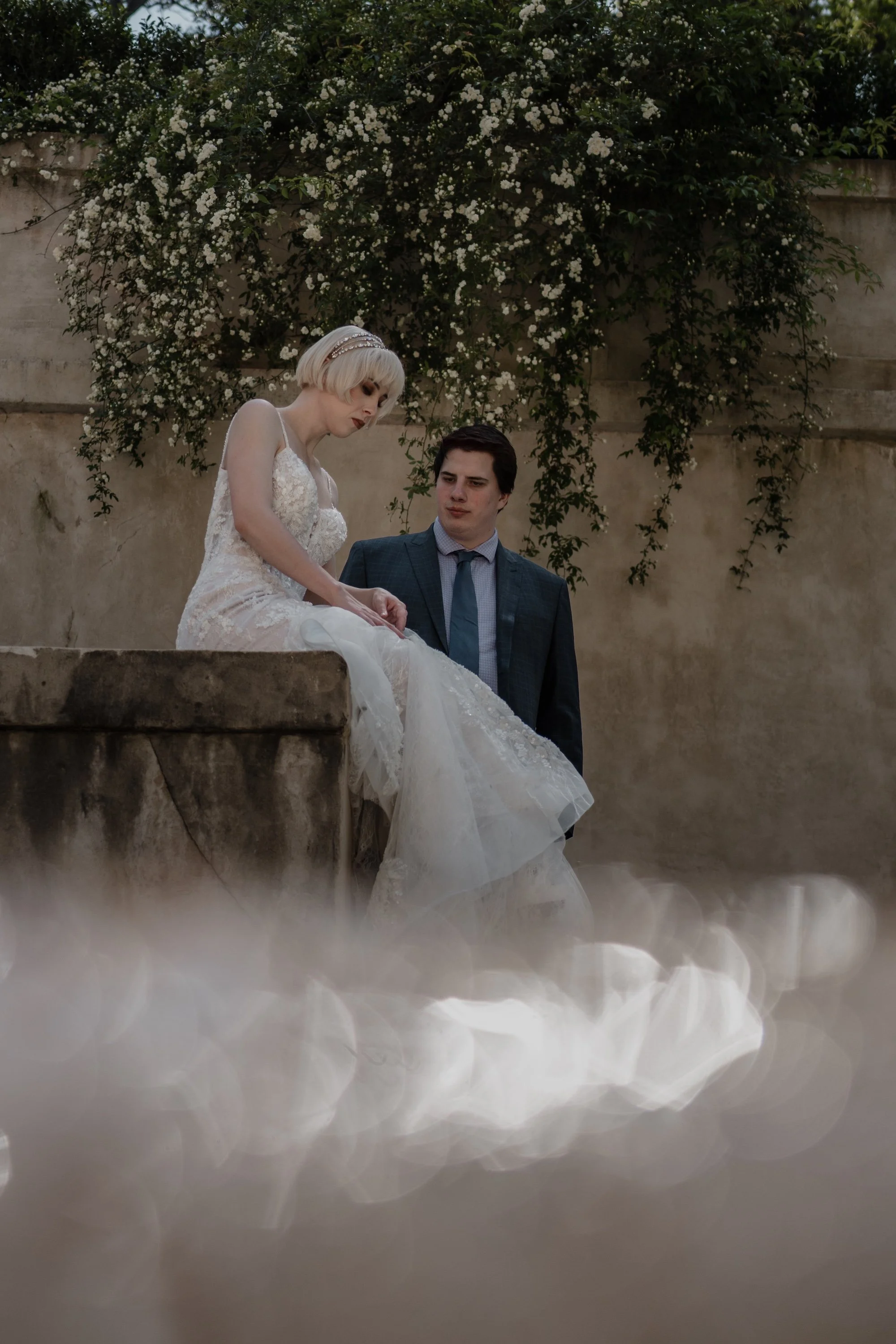 Bride and groom seated together on a stone ledge, editorial moment captured by The Edge Bali Wedding Photographer