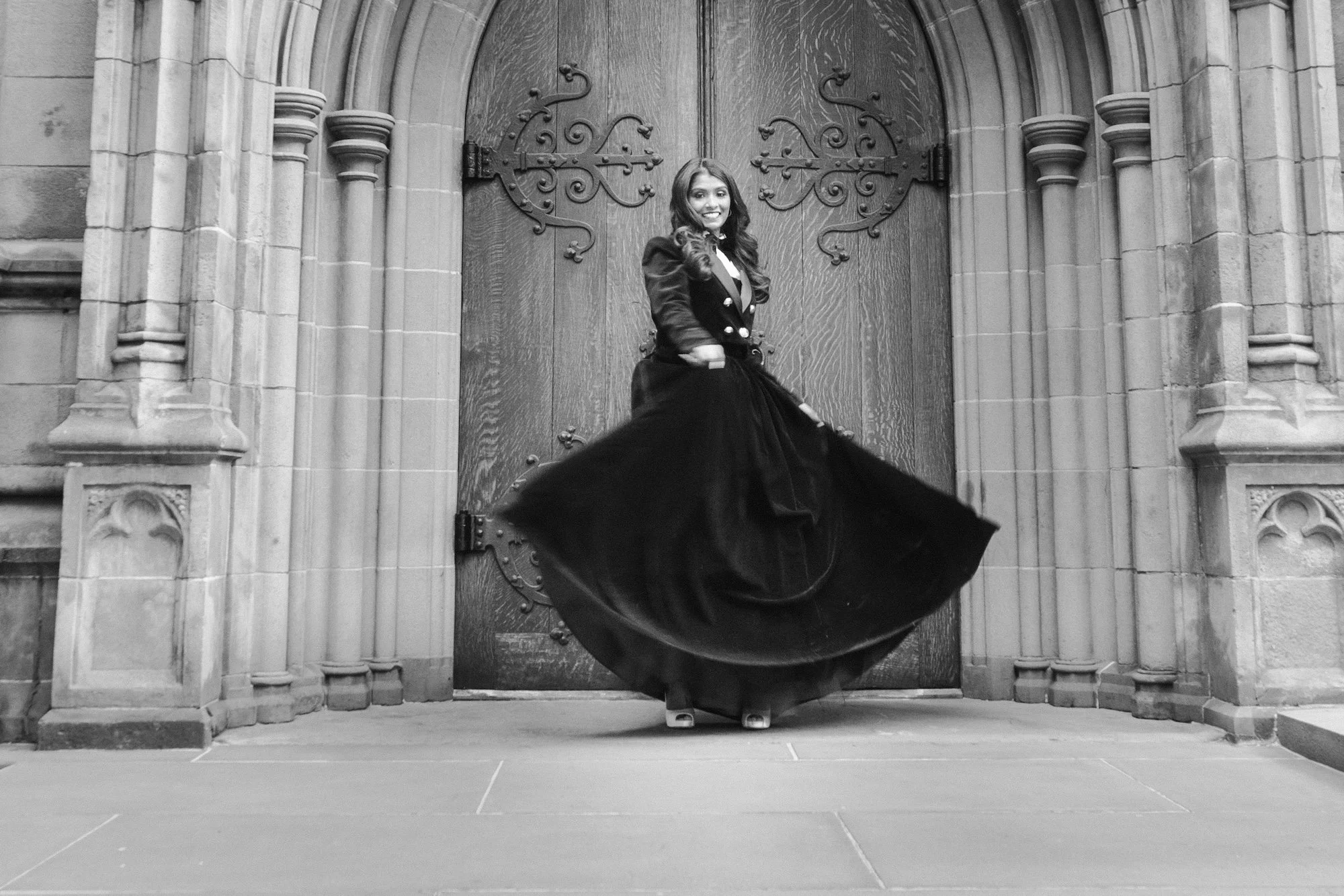 Sweeping black gown twirls in front of Trinity Church doors — 48 Wall Street Wedding Photographer.