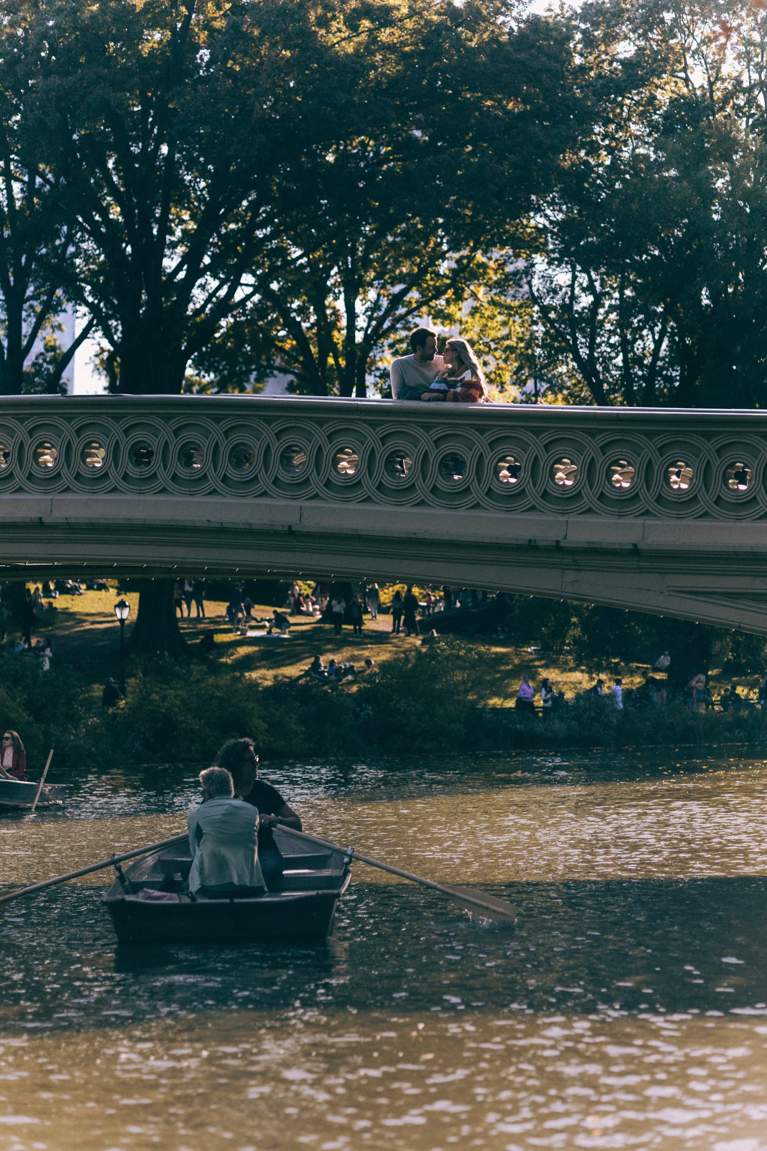 Romantic Central Park proposal with a couple rowing beneath Bow Bridge on The Lake.