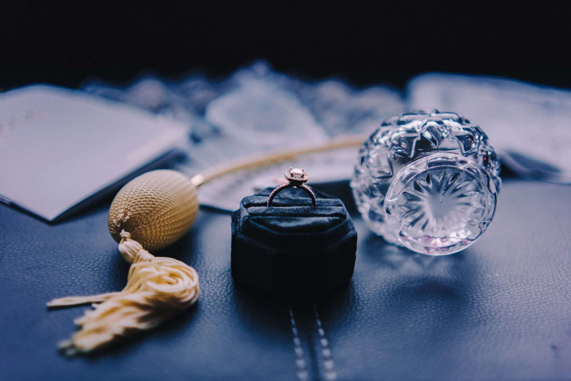 Editorial detail of wedding rings and jewelry styled with dramatic shadow and texture.