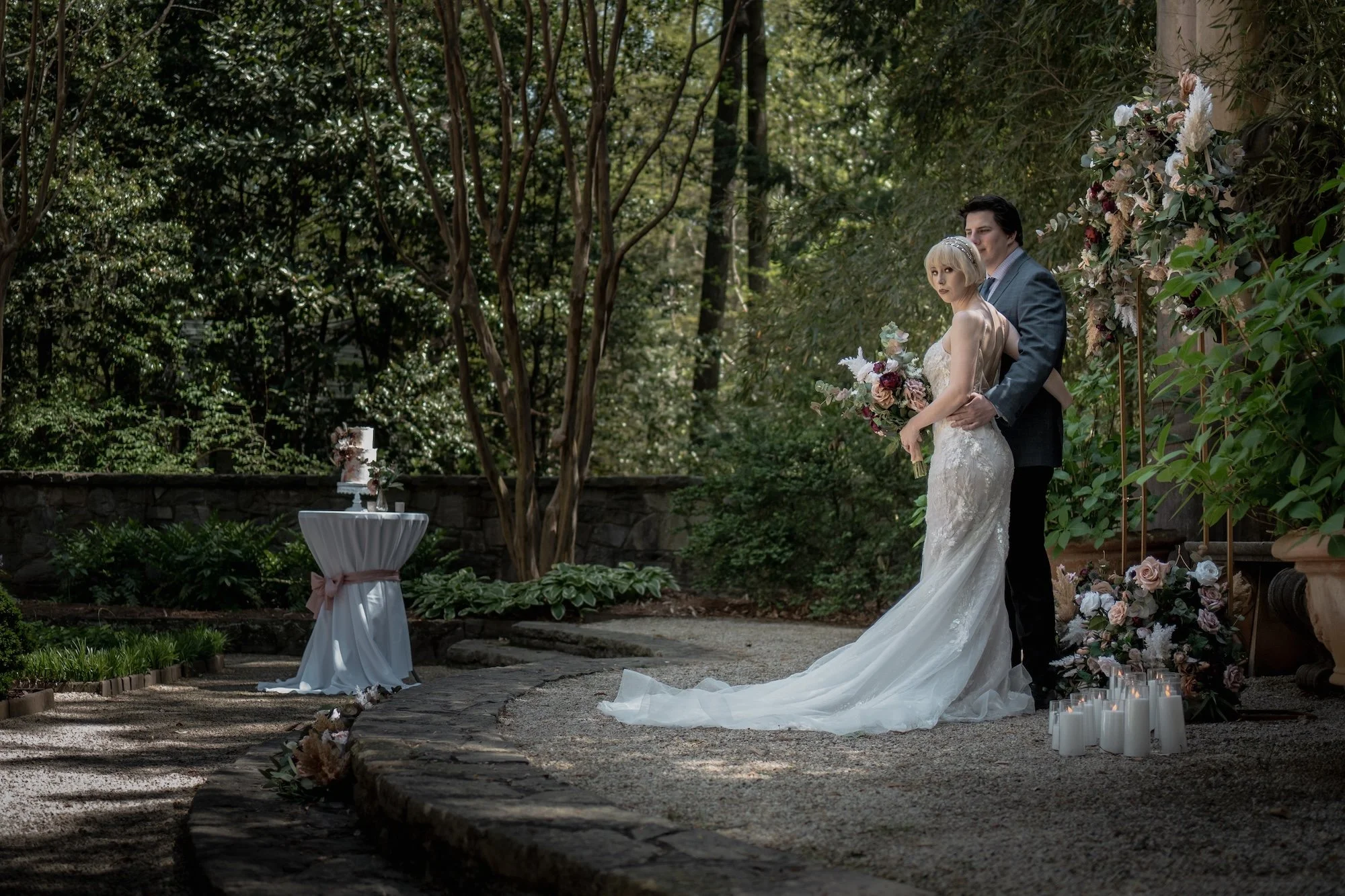 A couple walking across the lawn, the bride’s gown catching the light as the groom leads her forward, evoking a sense of timeless movement and romance.