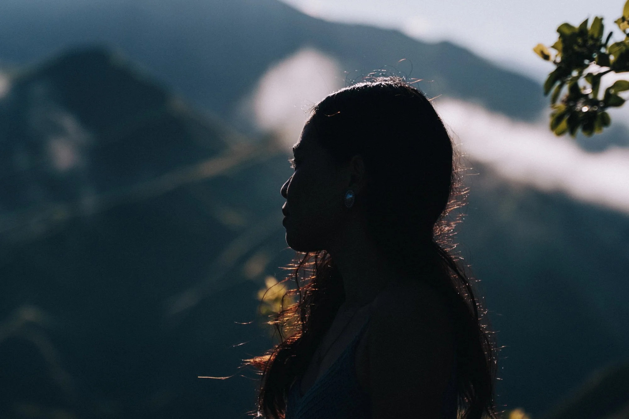 A woman in profile against mountain light, her silhouette framed in moody cinematic tones.