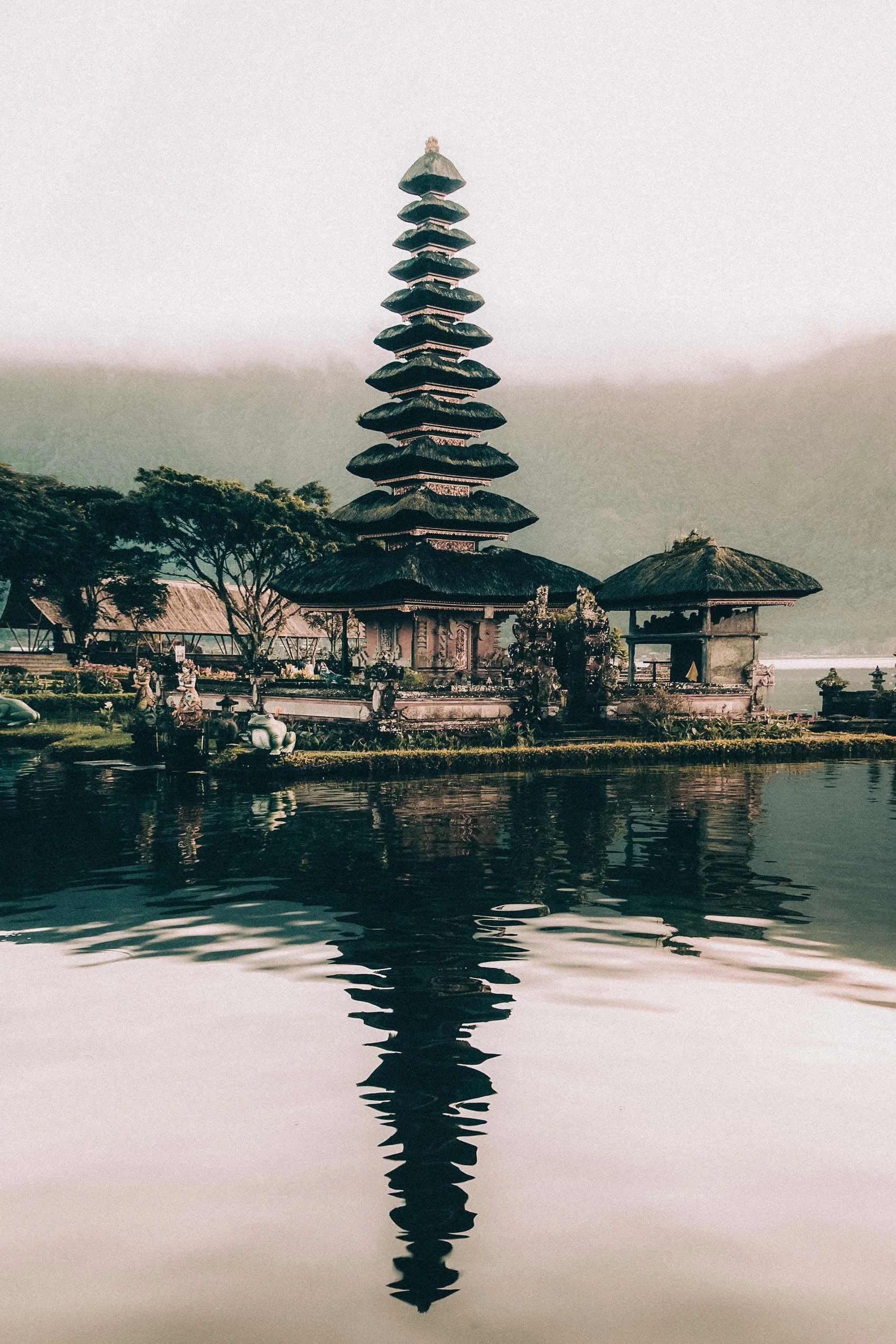 A Balinese temple reflected on still water, architecture that feels like a stage for cinematic vows.
