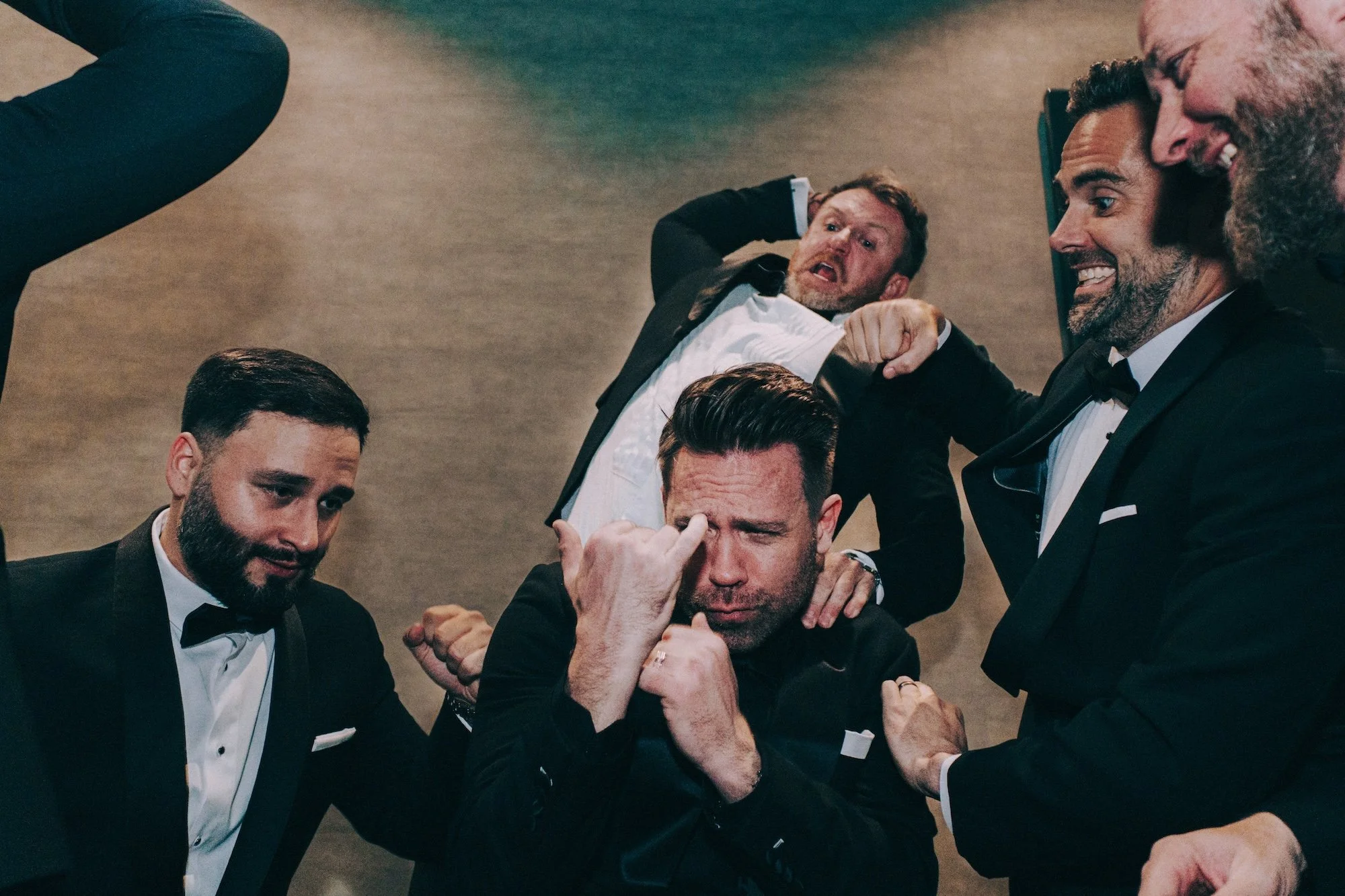 Groomsmen celebrating together with champagne, energy and laughter filling the frame.
edding.