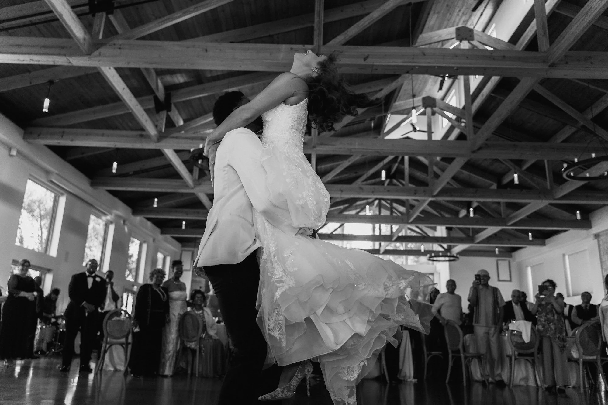A groom lifts his bride on the dance floor, laughter and motion blending in cinematic rhythm.