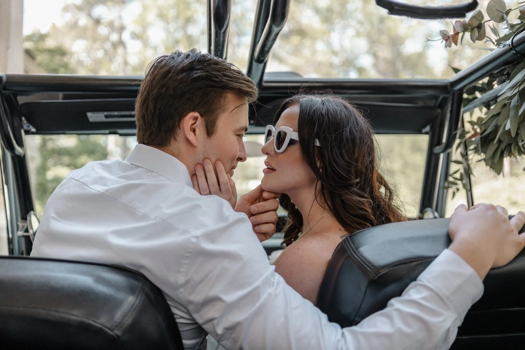 A groom touching his bride’s face with quiet tenderness inside a car, their eyes meeting with intimacy — Vietnam Wedding Photographer