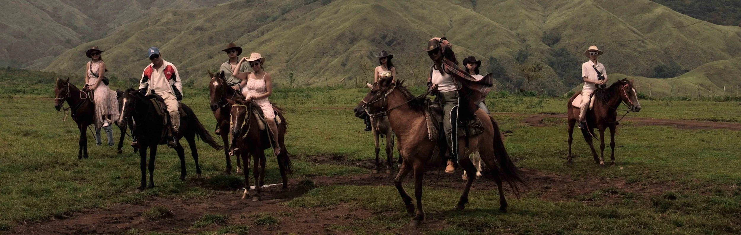 Riders on horseback moving across an open field, sunlight catching their movement in a cinematic frame.