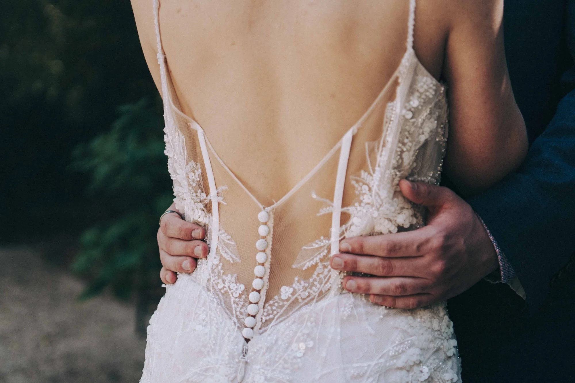 A groom’s hands rest gently on the back of his bride’s lace gown, the detail of fabric and touch creating a cinematic editorial frame, captured by a Kyoto Wedding Photographer.
