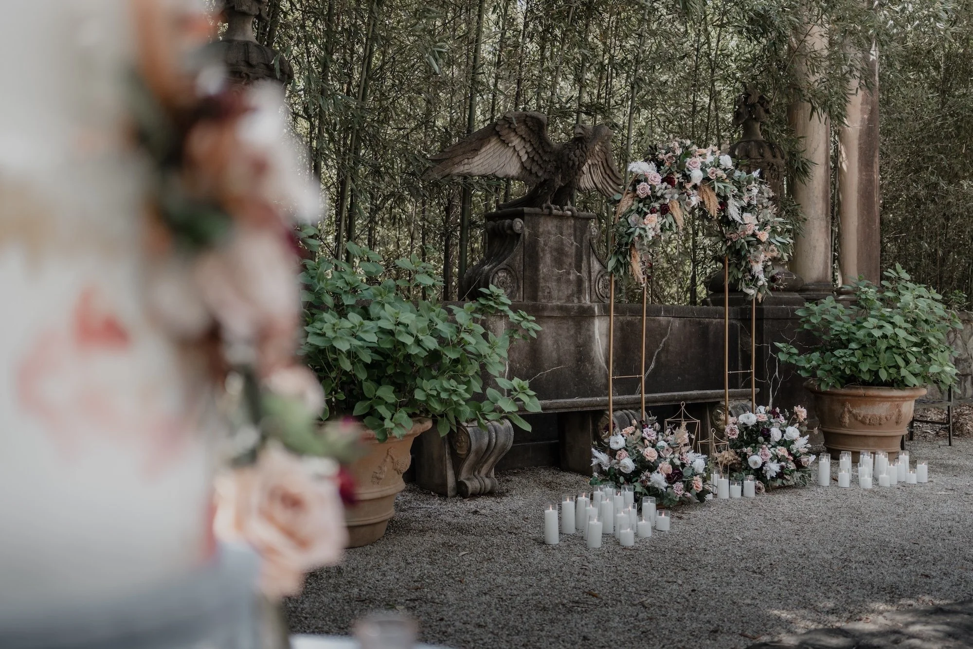Ceremony arch surrounded by florals and candles, details styled to heighten the atmosphere.