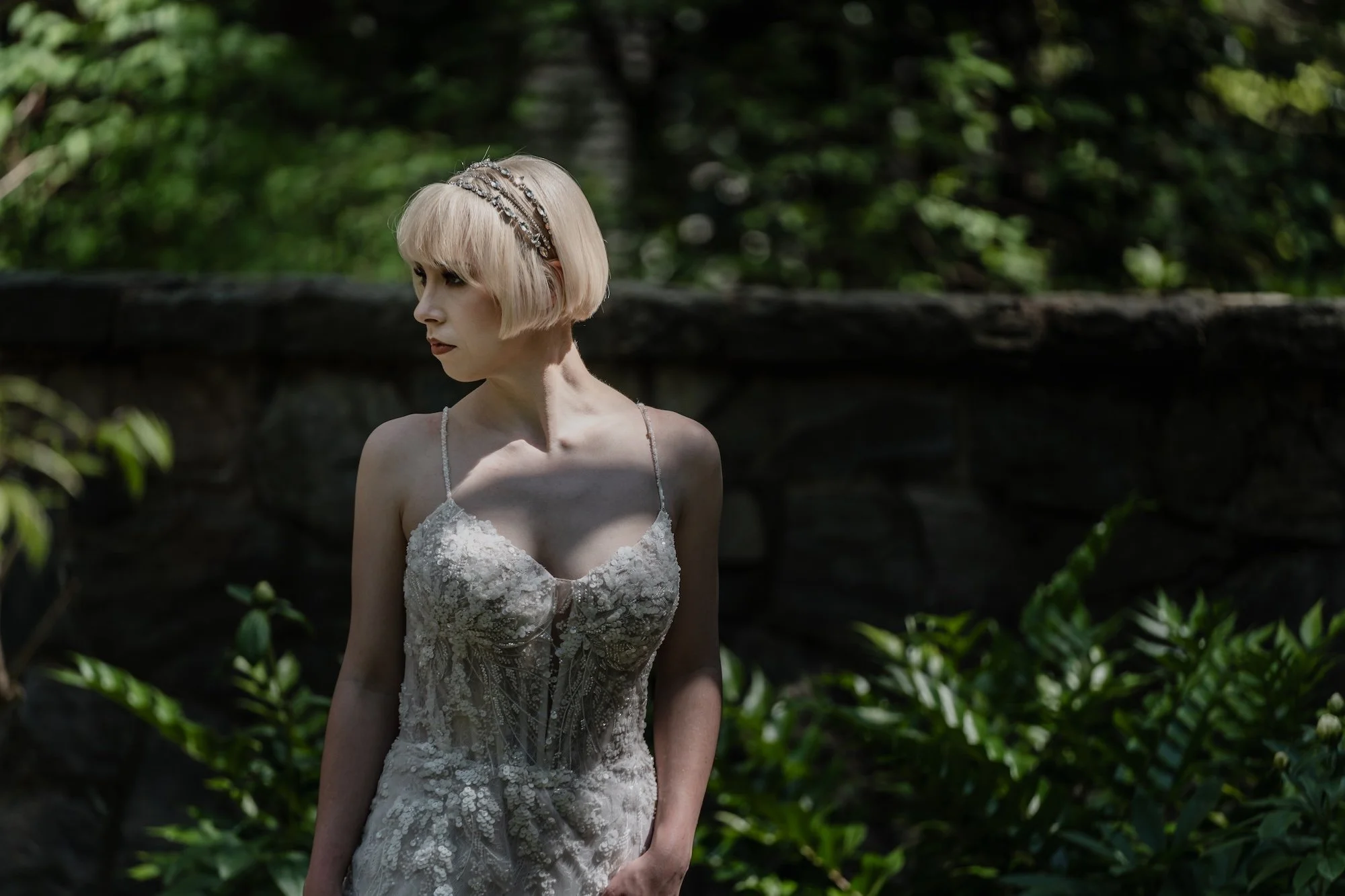 A bride looks over her shoulder, editorial tones highlighting her gown and the softness of light on her face.