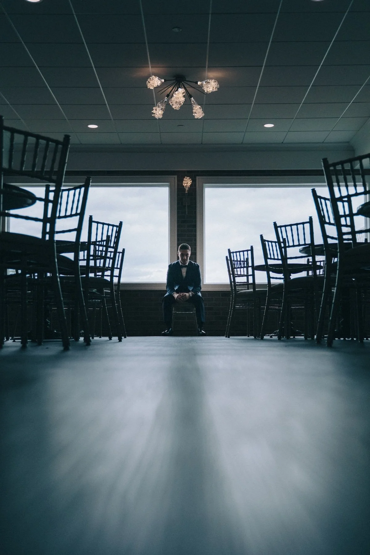 Rows of chairs in an empty hall, light streaming through tall windows creating a cinematic mood.