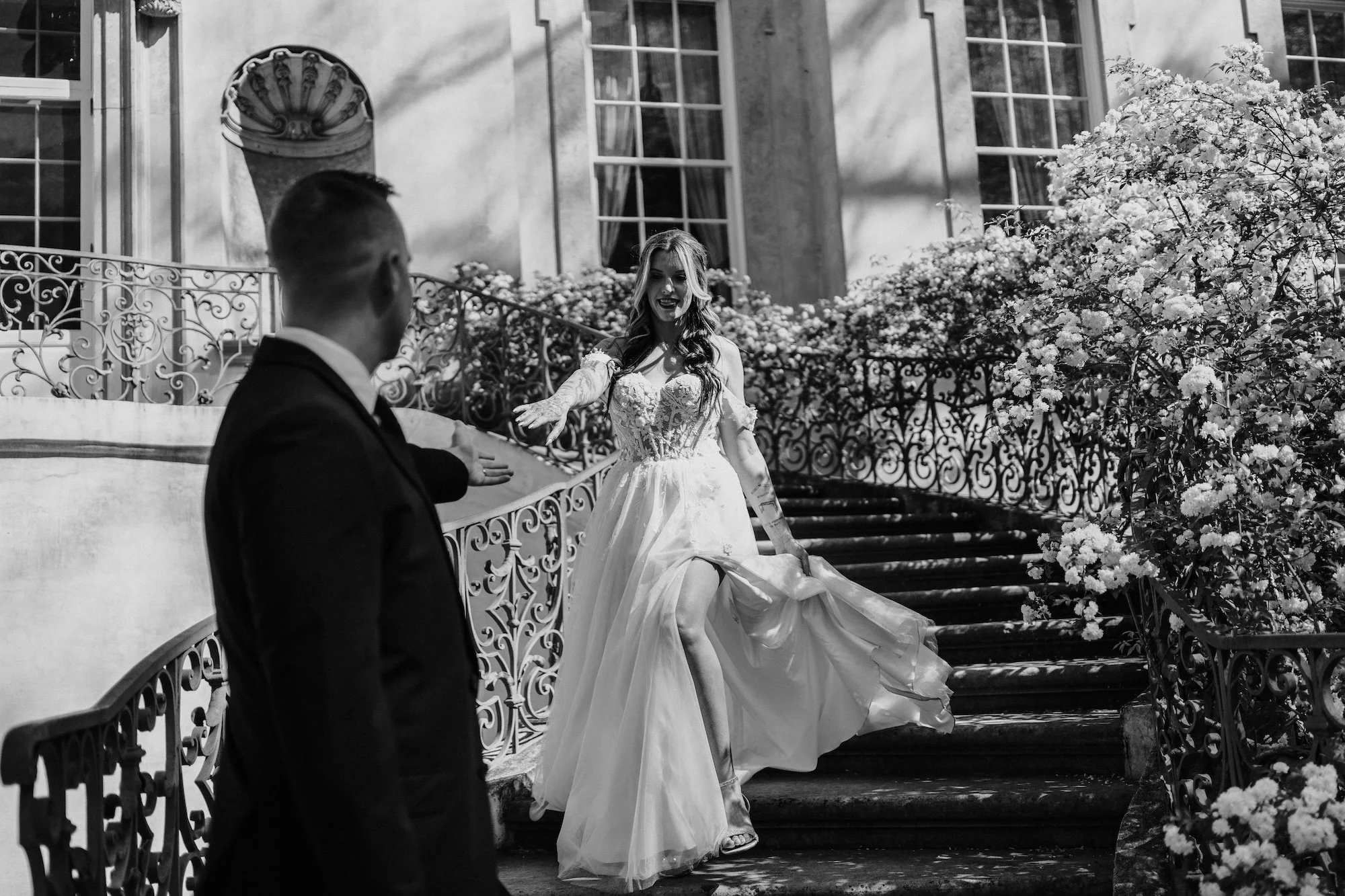A groom turns to see his bride, her dress caught mid-motion, creating a cinematic frame shaped by light and lines.