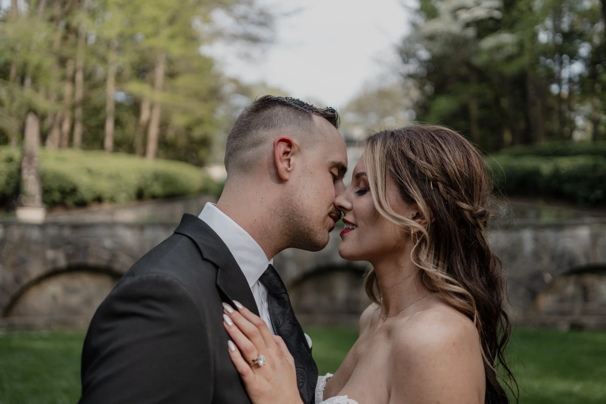 A groom leaning in to kiss his bride as they stand face to face near the water, cinematic storytelling through the lens of a Destination Wedding Photographer.