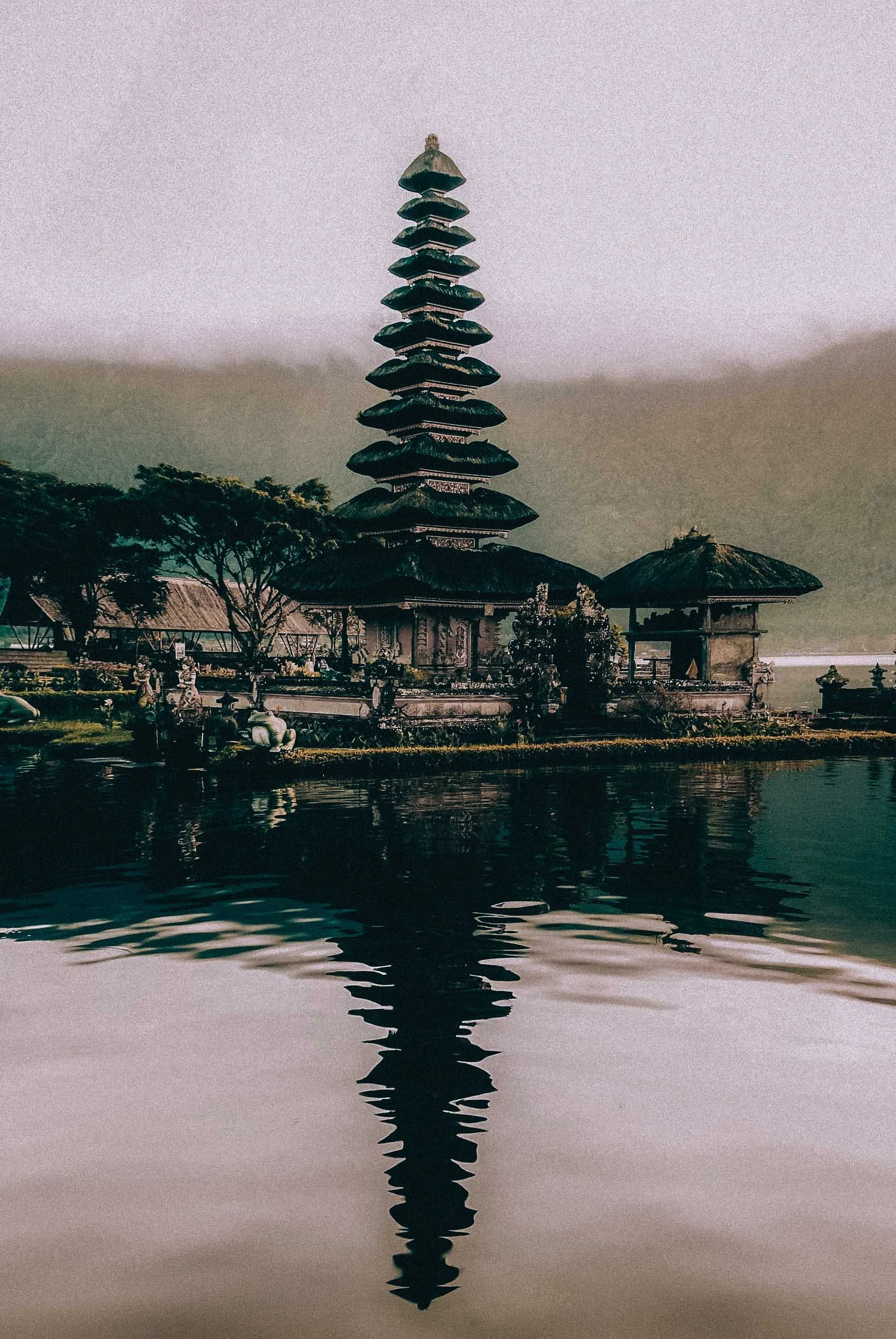 Bride and groom stand together by a temple in Balireflection pool, framed in soft morning light, captured by Viceroy Bali Wedding Photographer