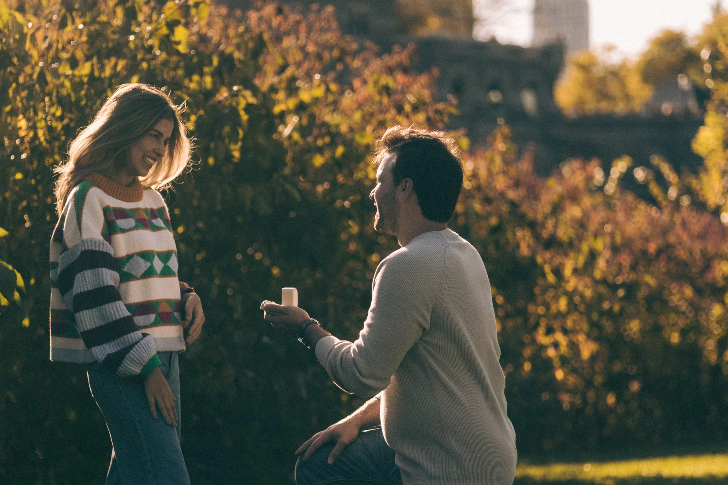 Surprise proposal in Central Park, groom-to-be down on one knee in the golden light.
