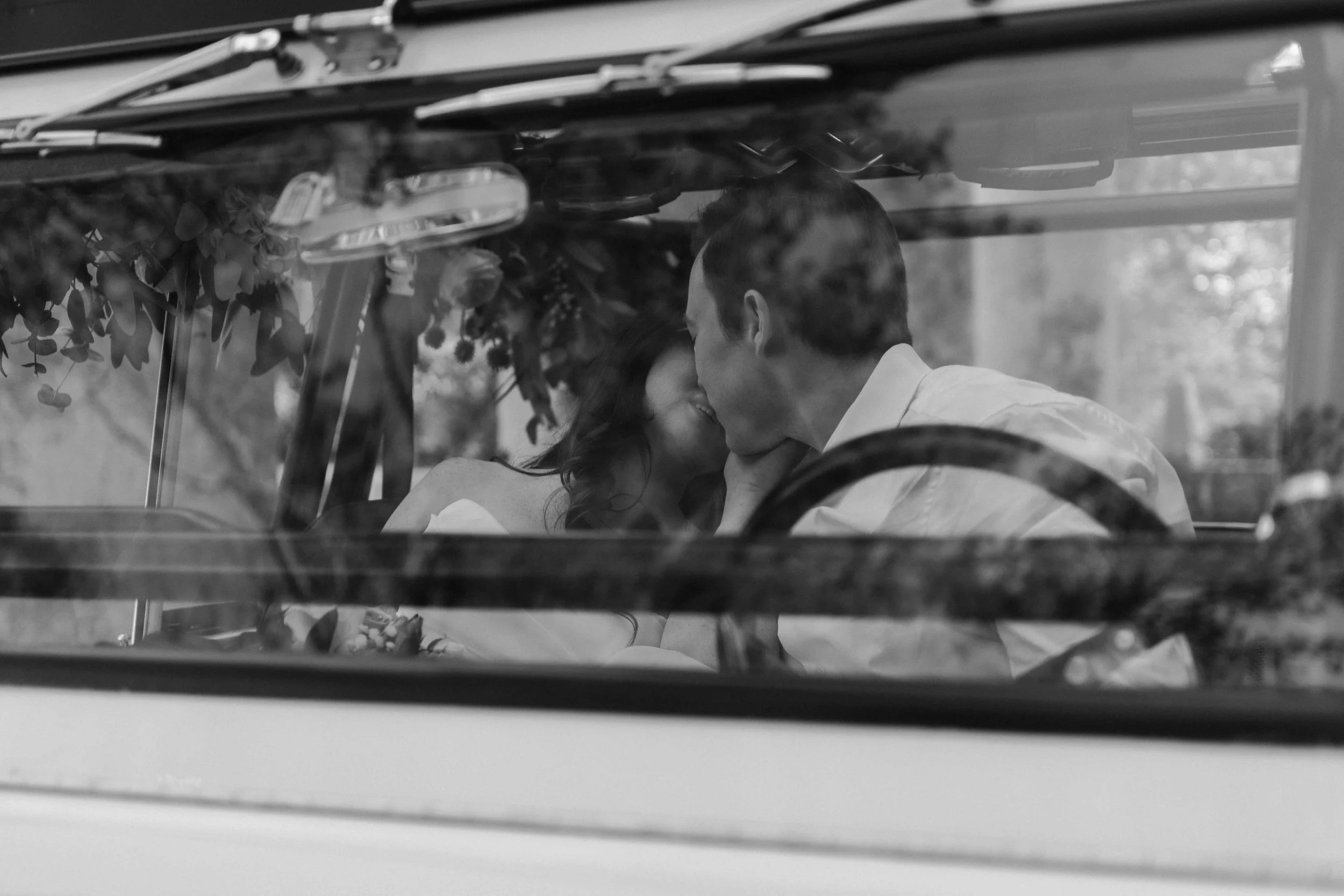 A couple sits close inside a vehicle, leaning toward each other as reflections layer the glass, framed by a Fragmented Memories prenup photographer.