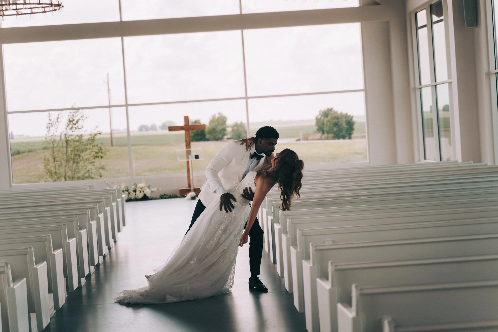 A bride and groom walking down the aisle together, their steps aligned as light streams through the windows.