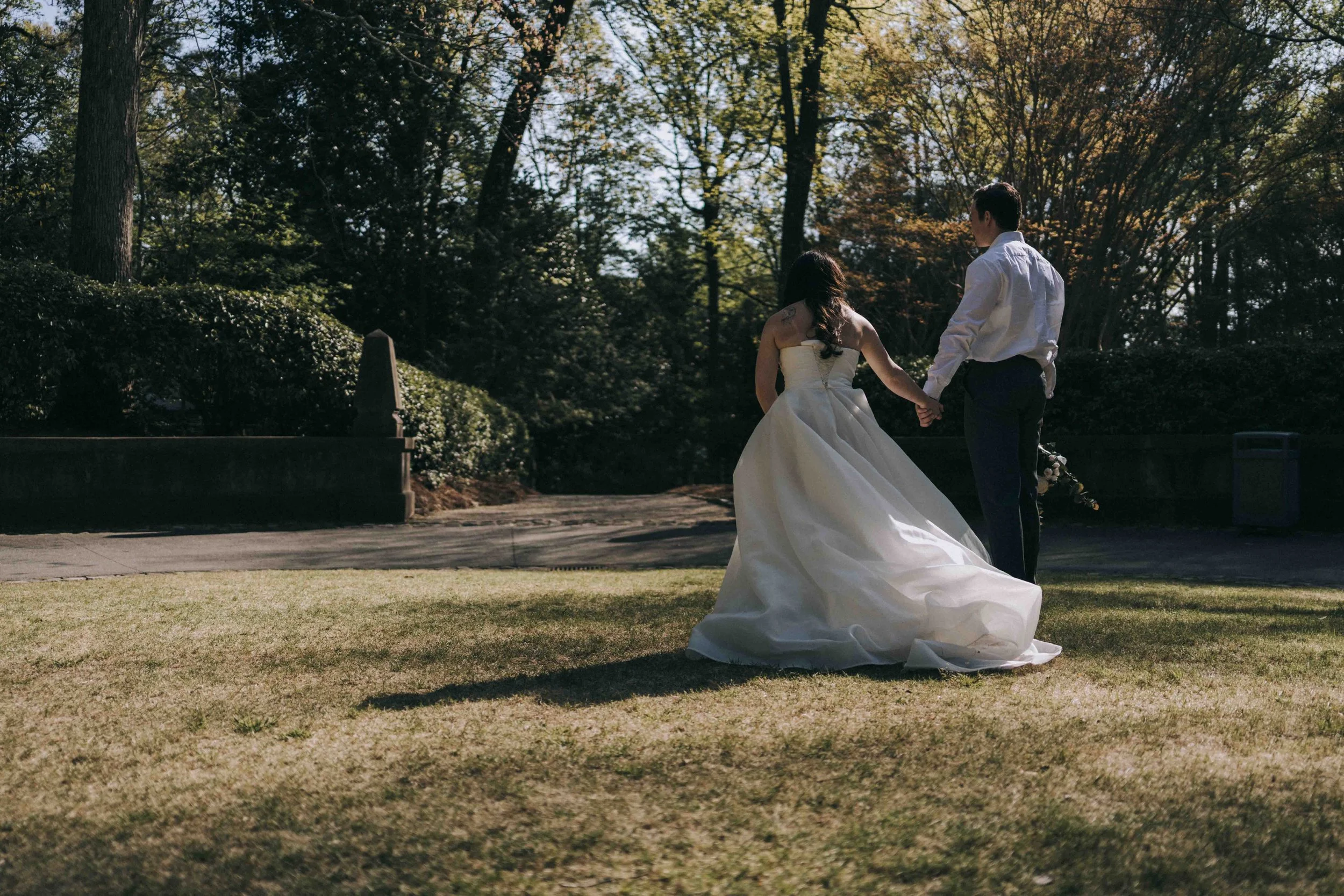 Bride and groom walking hand in hand through sunlit gardens — captured by The Edge Bali Wedding Photographer.
