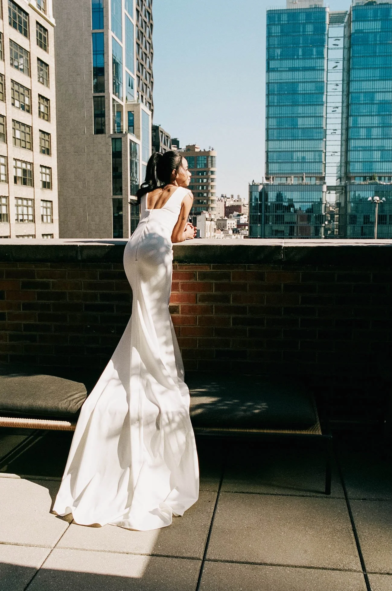 Bride looks over the city skyline while holding her bouquet, veil catching the light, captured by Caz Isaiah inspired by Bali