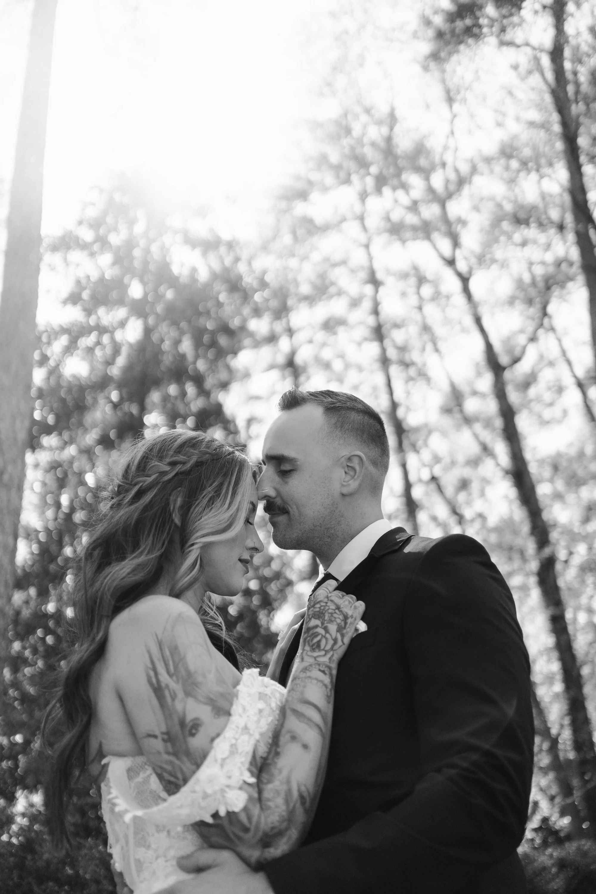 A bride and groom share a kiss, soft light wrapping their embrace with warmth and intimacy.