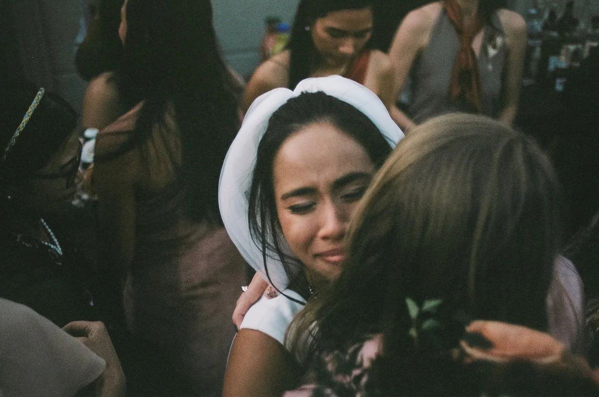 Bride embraces a guest with emotion, veil framing her face