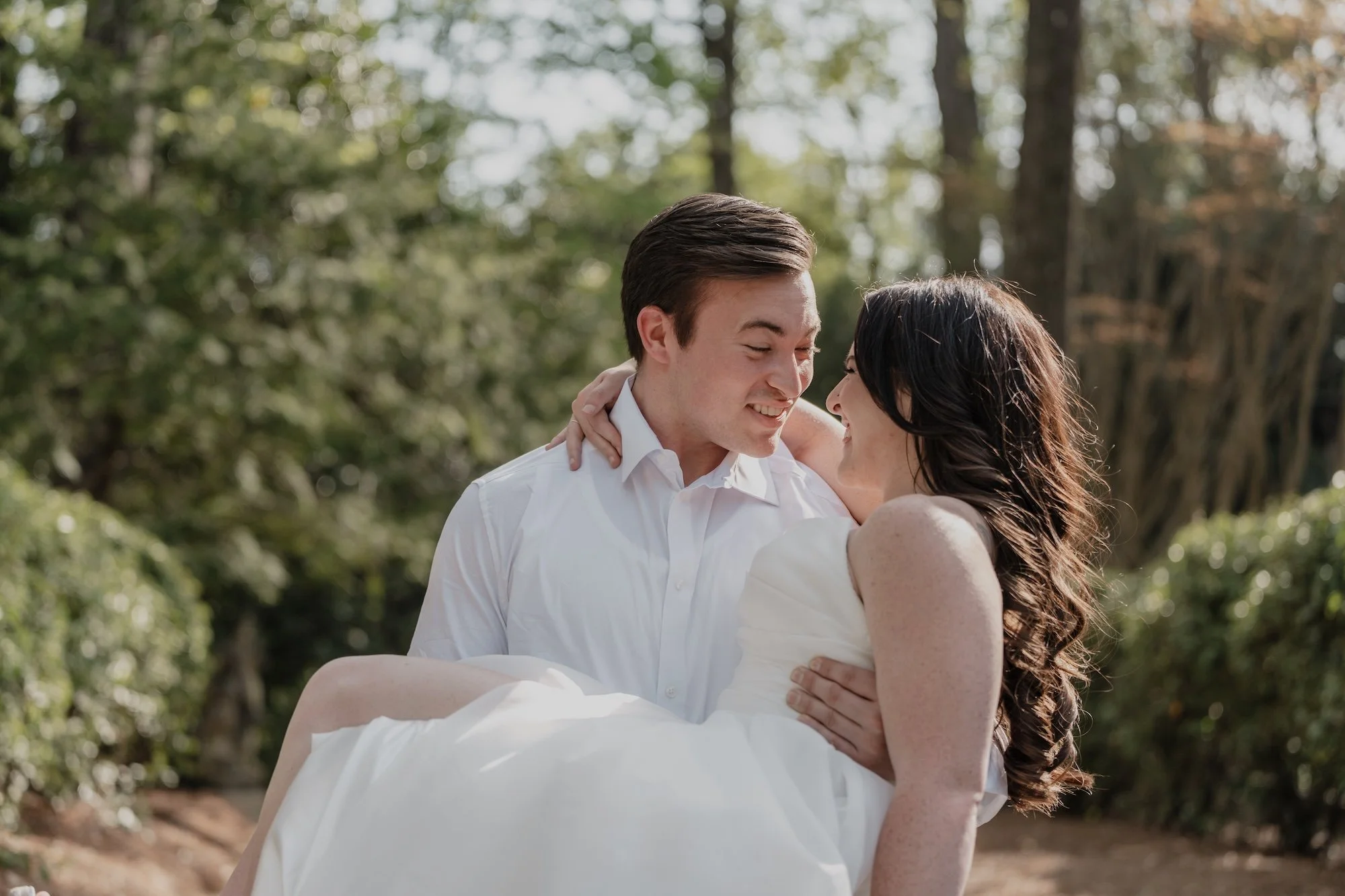 groom lifting up bride surrounded by greenery