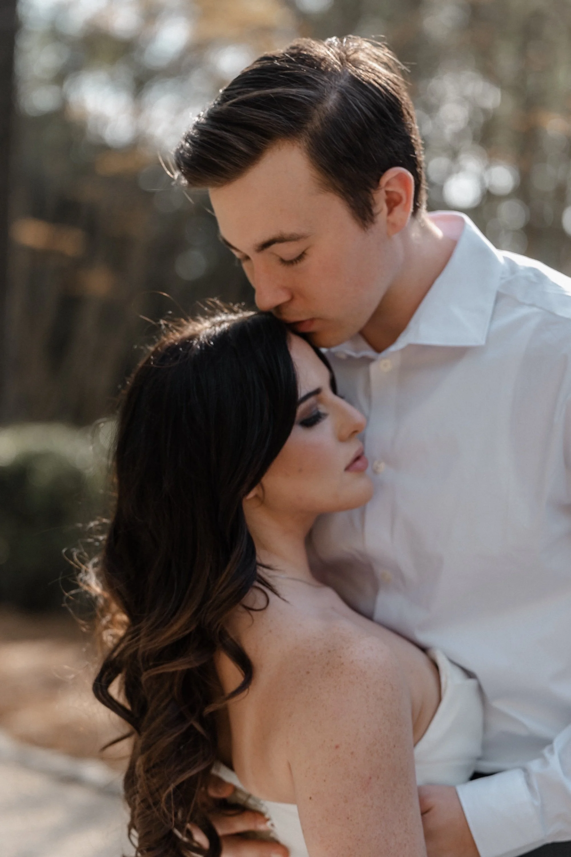 A groom kisses his bride’s forehead as she closes her eyes, framed tightly in intimate light — Villa Erba wedding photographer style.
