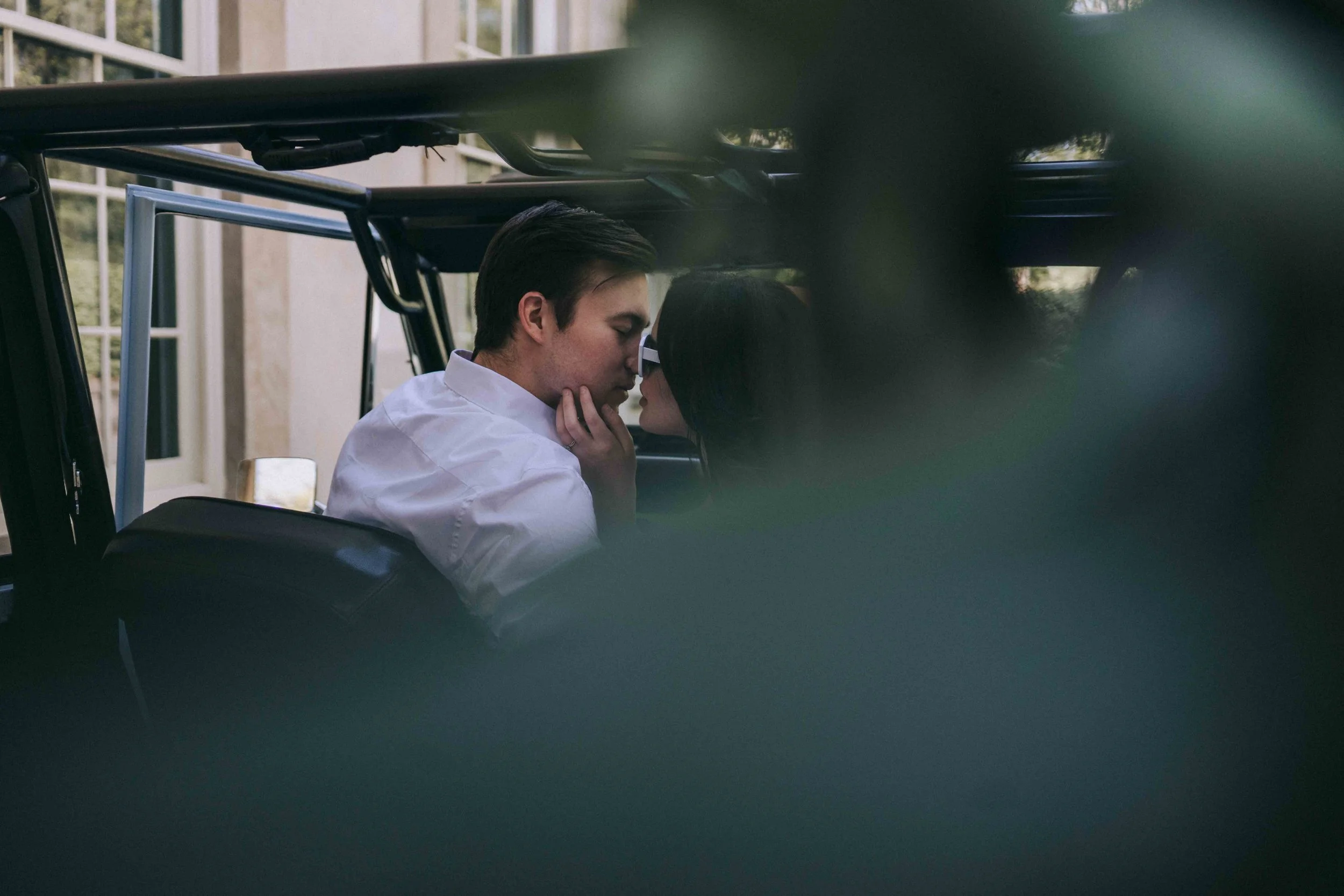 A couple shares a quiet kiss inside a parked vehicle, bodies angled inward, hands resting gently, observed by a Fragmented Memories prenup photographer.
