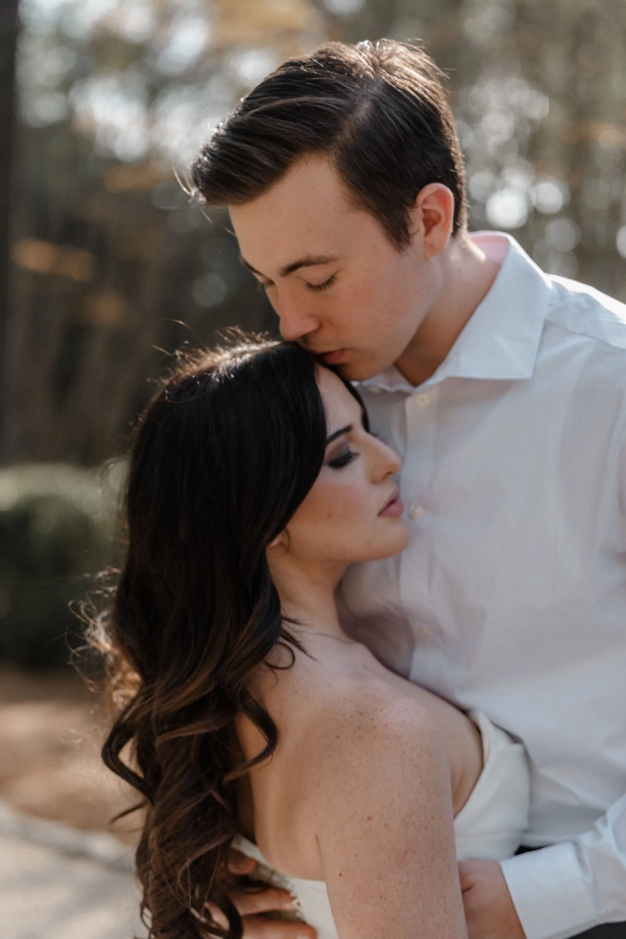 A groom presses a kiss to his bride’s forehead, their embrace filled with intimacy and stillness, captured by Caz Isaiah.