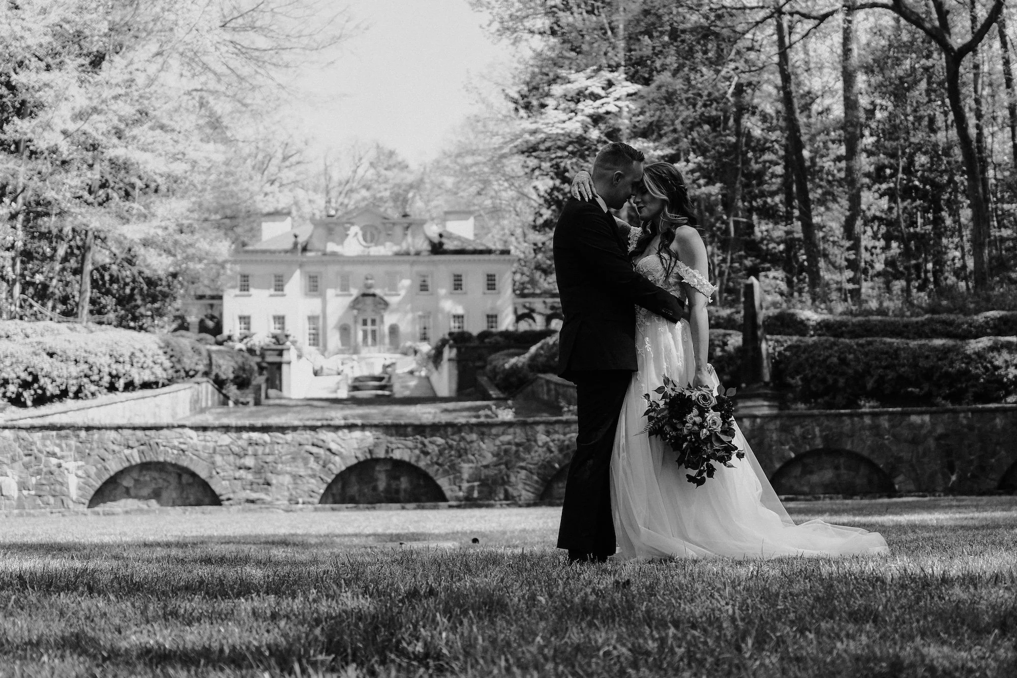 A couple embraces before an old stone bridge, Editorial Wedding Photographer storytelling blending intimacy and grandeur.