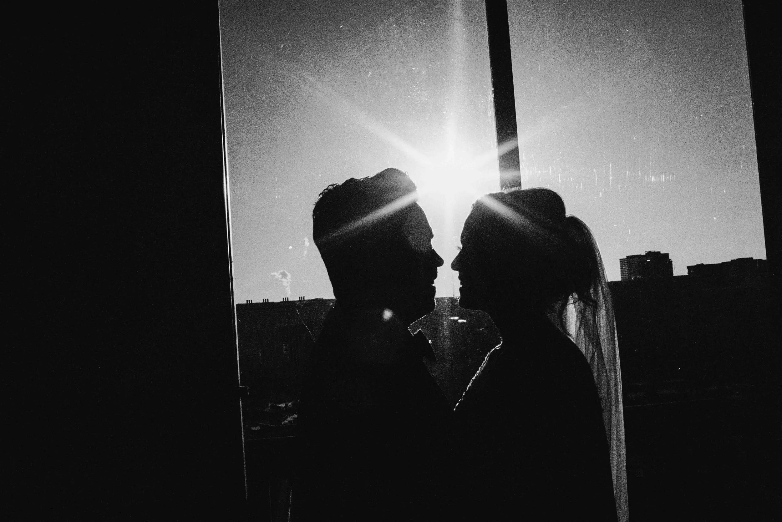 Silhouette of a couple in front of window, light spilling between them as they share a quiet embrace, inspired by Viceroy Bali weddings