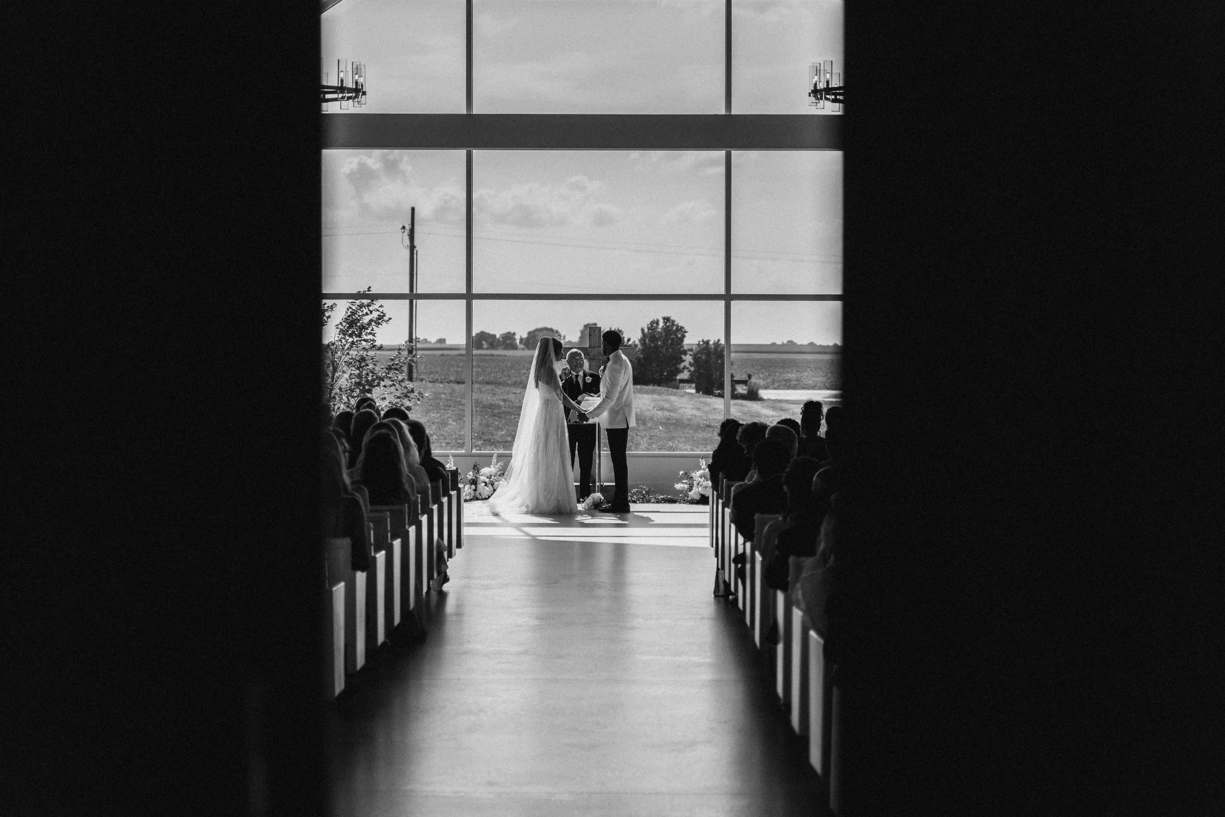 Bride and groom exchange vows before a wall of light, framed by soft silhouettes and natural countryside tones — captured by Caz Isaiah, Topas Ecolodge Sa Pa wedding photographer.