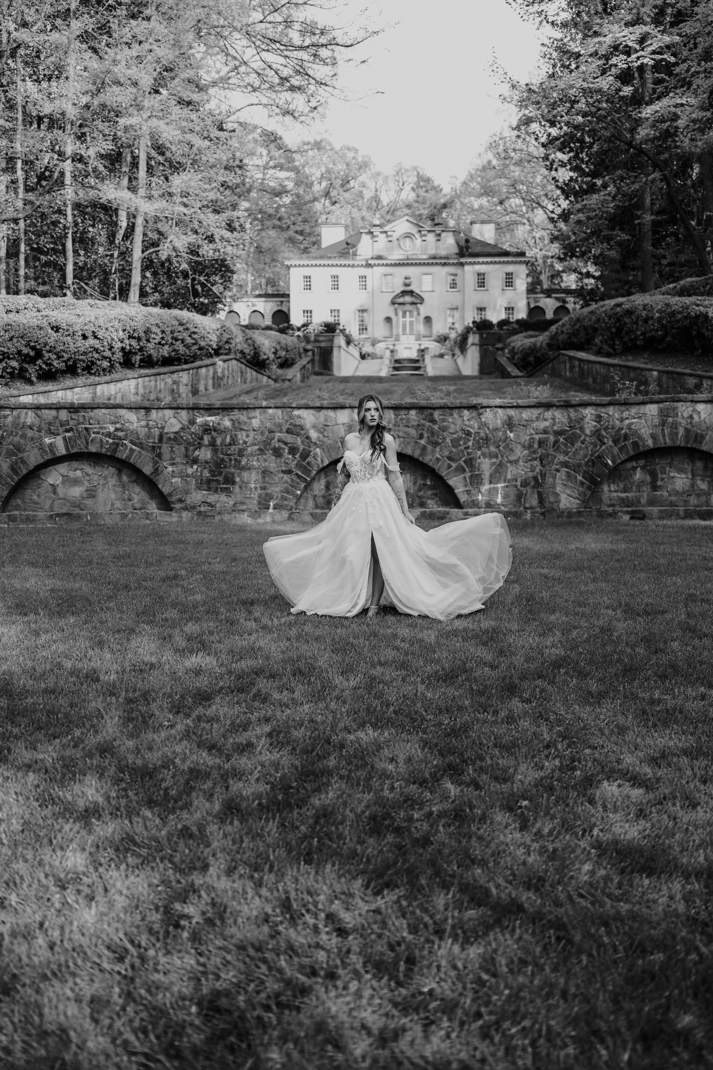 The bride’s dress cascades across the lawn as she walks toward the villa, a cinematic silhouette captured from behind.