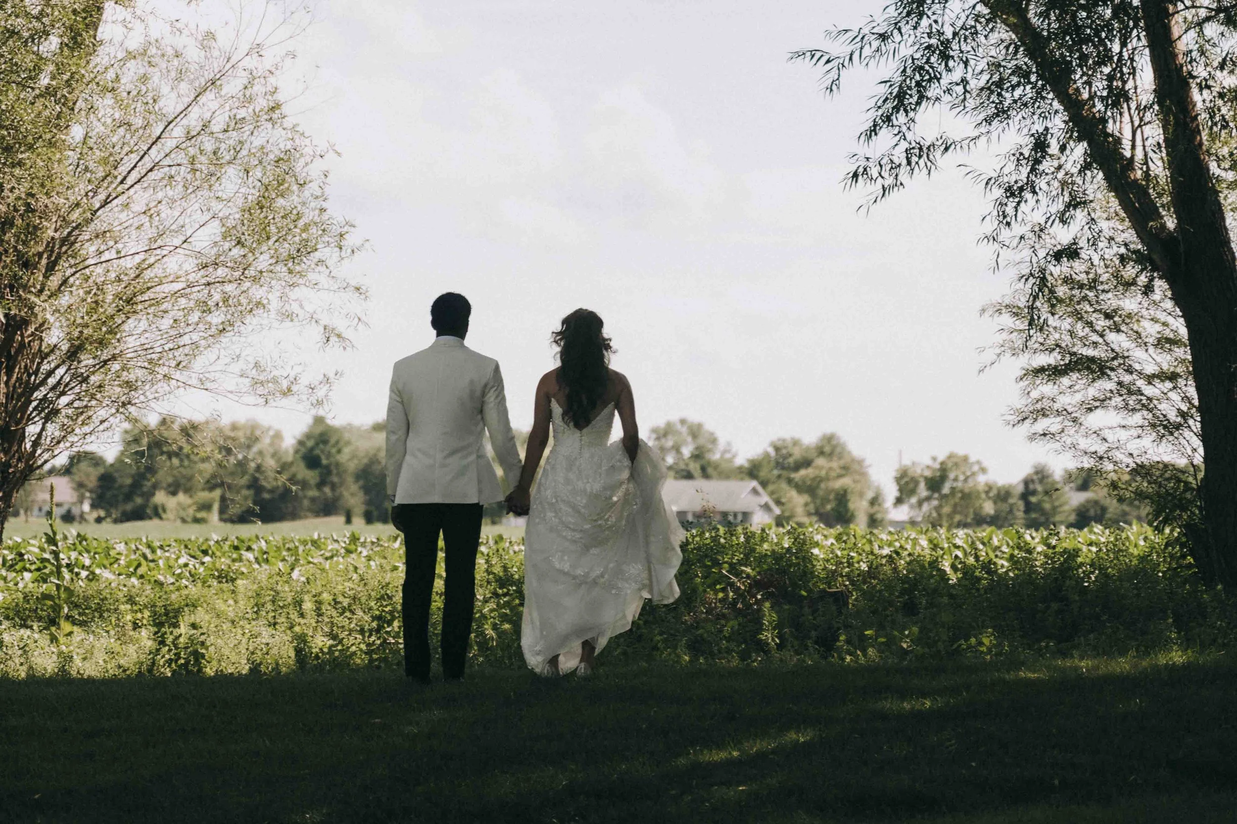 Bride and groom walk hand in hand through open fields beneath soft afternoon light, cinematic and timeless — inspired by Awasi Patagonia’s natural stillness.