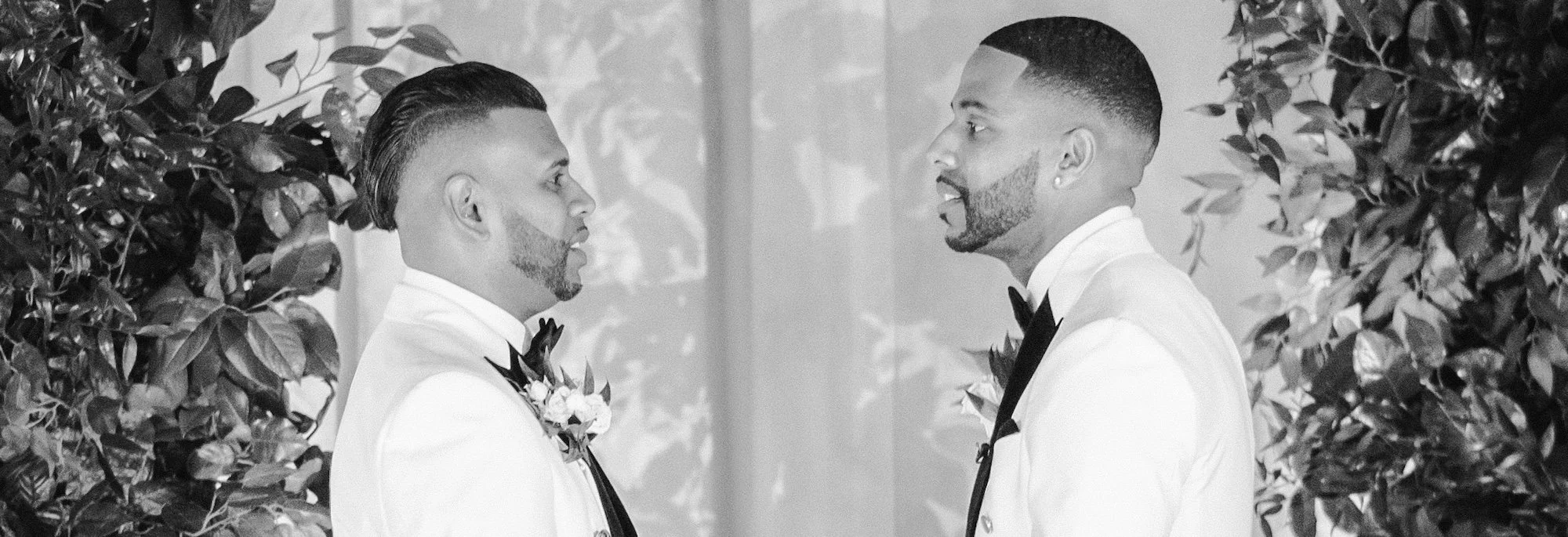 Black and white portrait of the grooms facing each other, framed in soft ceremony light — 48 Wall Street Wedding Photographer.