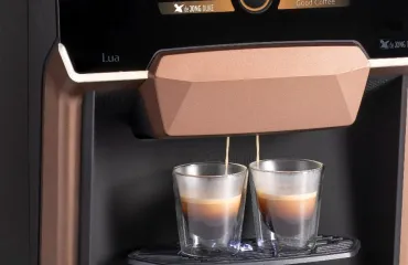 Close-up of a bean-to-cup coffee machine dispensing two espressos.