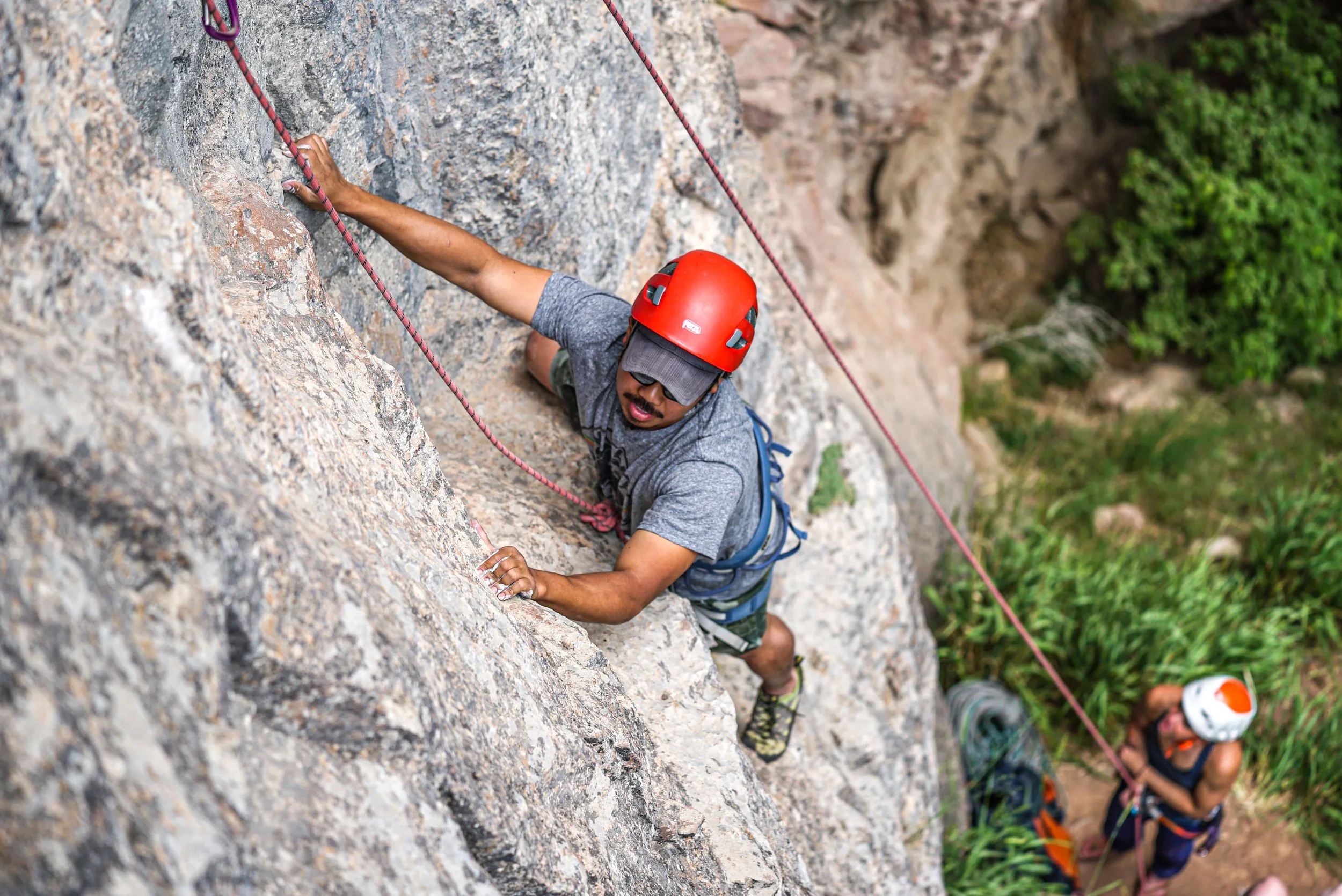 A climber in a red helmet is toprope rock climbing in Rifle Mountain Park