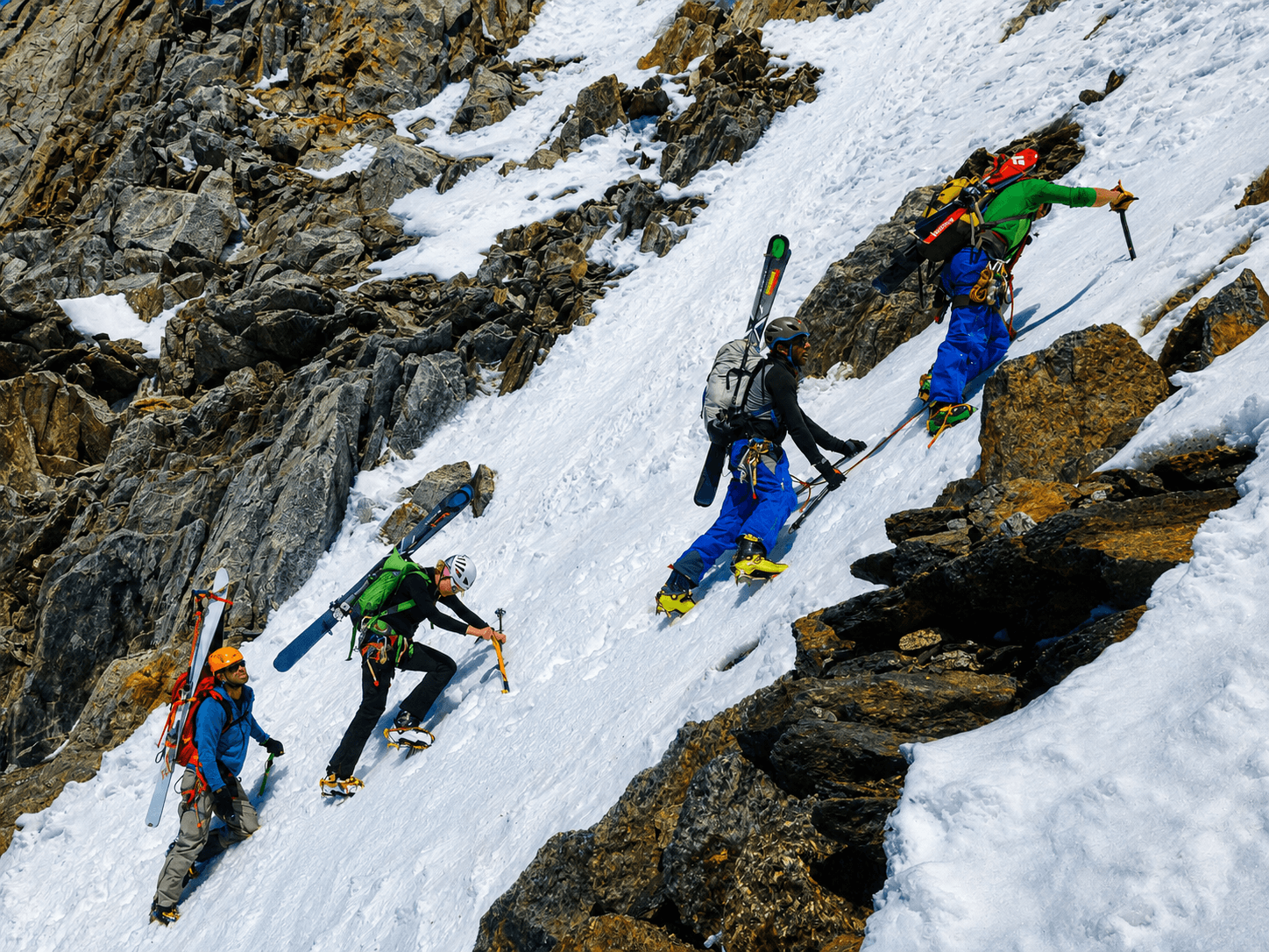 A group of skiers climb a steep snow slope with skis on their back.