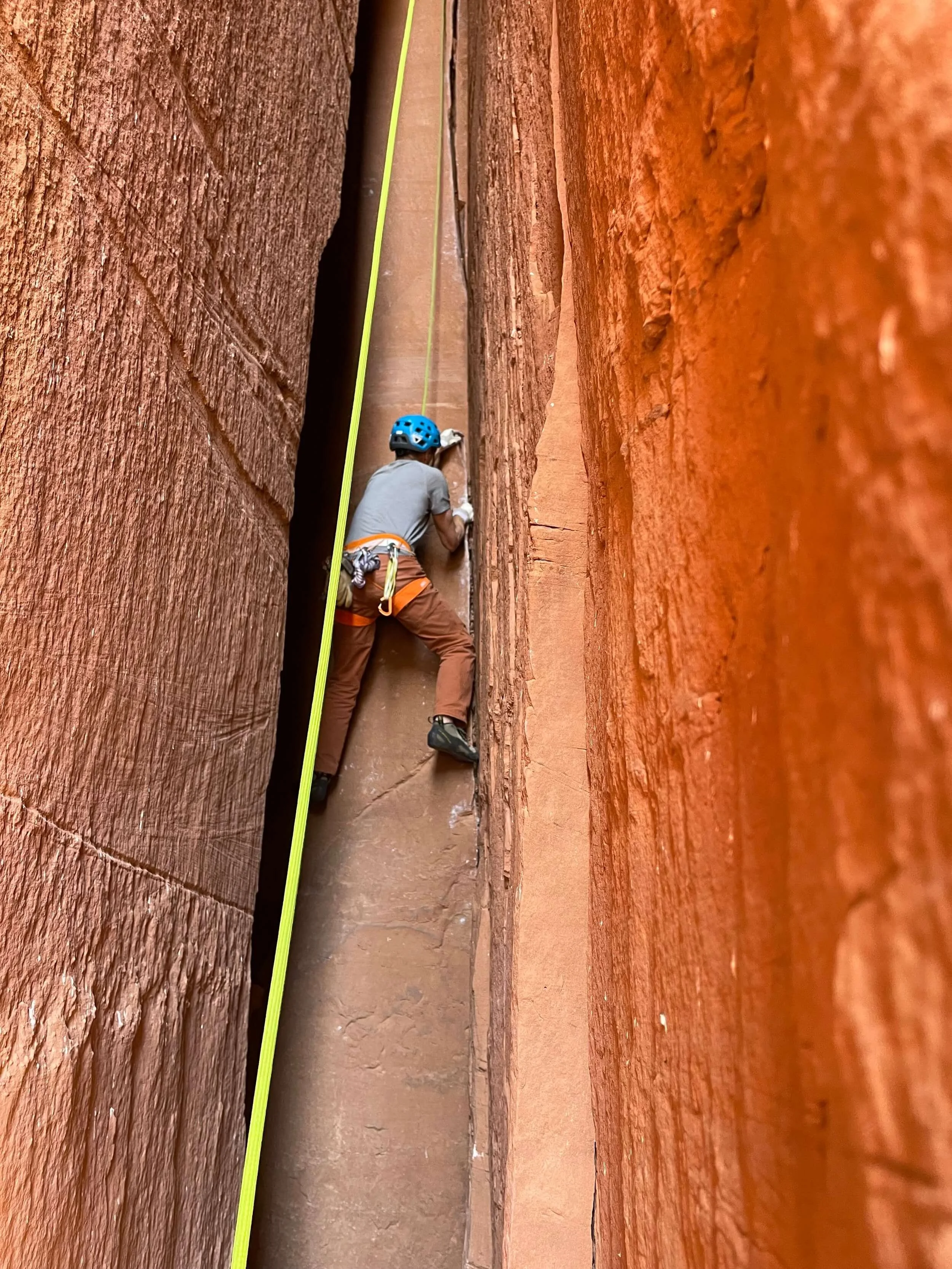 A climber in a blue helmet is toproping a chimney in Escalante Canyon, near Grand Junction.
