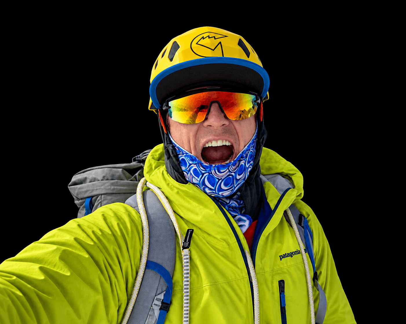Skyward Mountaineering founder and IFMGA Guide, Vince Anderson is smiling on the summit of Peak 11,300 in Alaska. He is wearing yellow jacket and yellow helmet.
