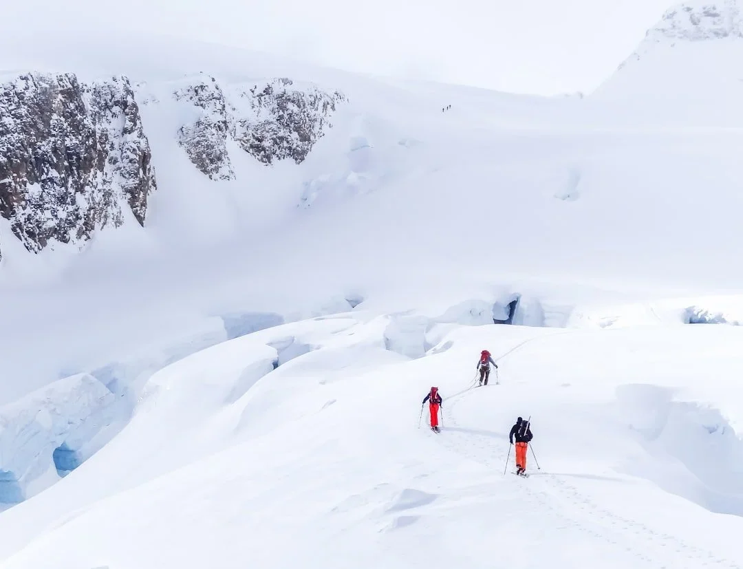 A team of three skiers traverse between crevasses on a glacier on Mount Baker.