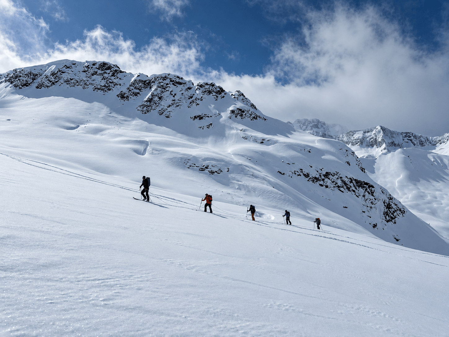 A group of skiers touring uphill on a glacier during a ski mountaineering expedition in Alaska.