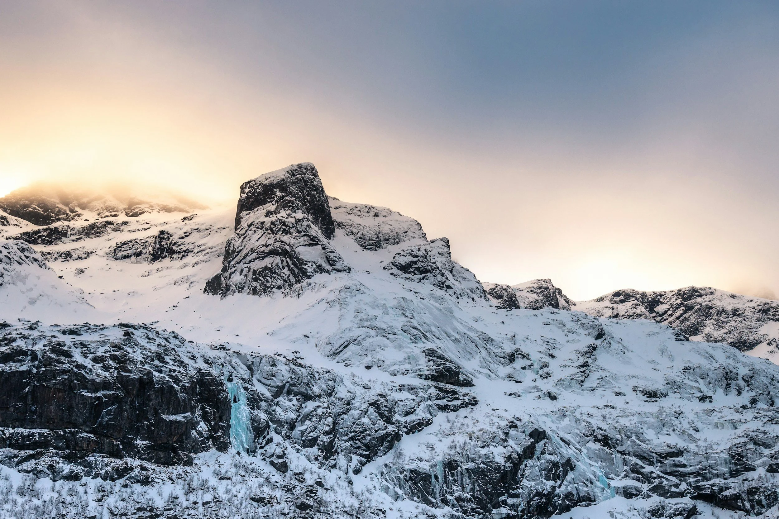 A frozen waterfall spills out of a steep cliff in Norway.