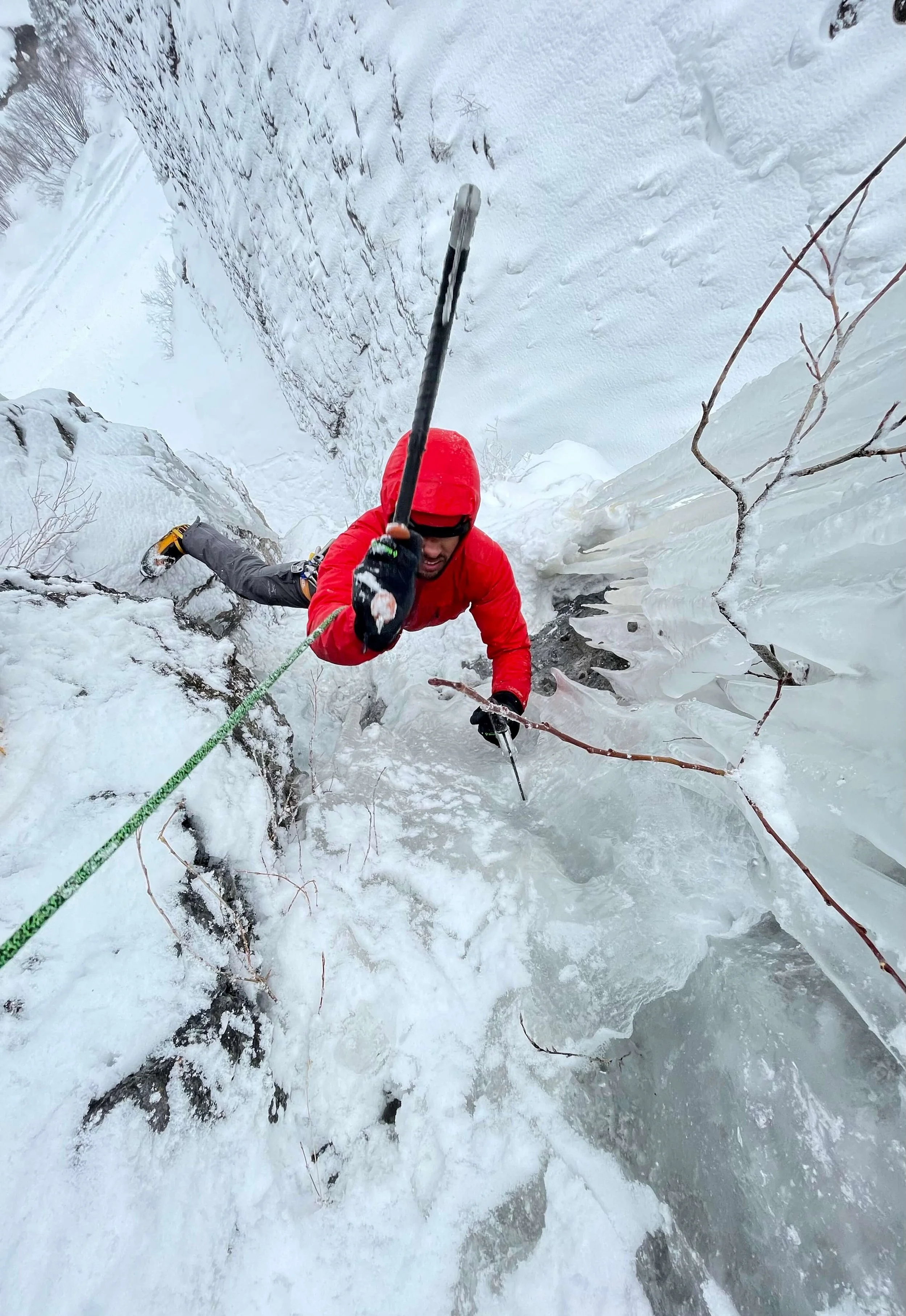 A climber in a red jacket is swinging his ice tool while toproping a climb at the Skylight Area of Camp Bird Road in Ouray.