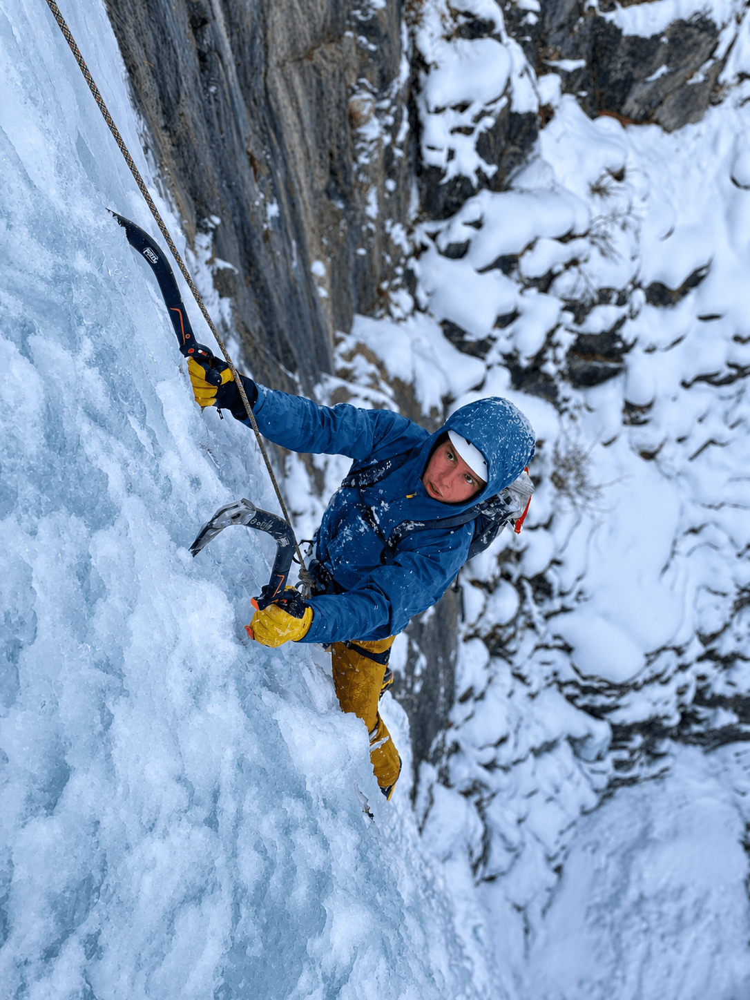A climber in a blue jacket is following a steep pitch of ice on Ouray's classic route, Horsetail Falls.