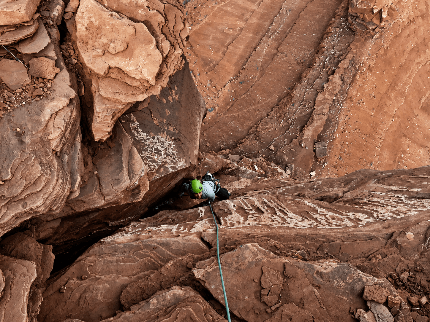 A woman in a green helmet is climbing the final pitch to the summit of Casleton Tower.