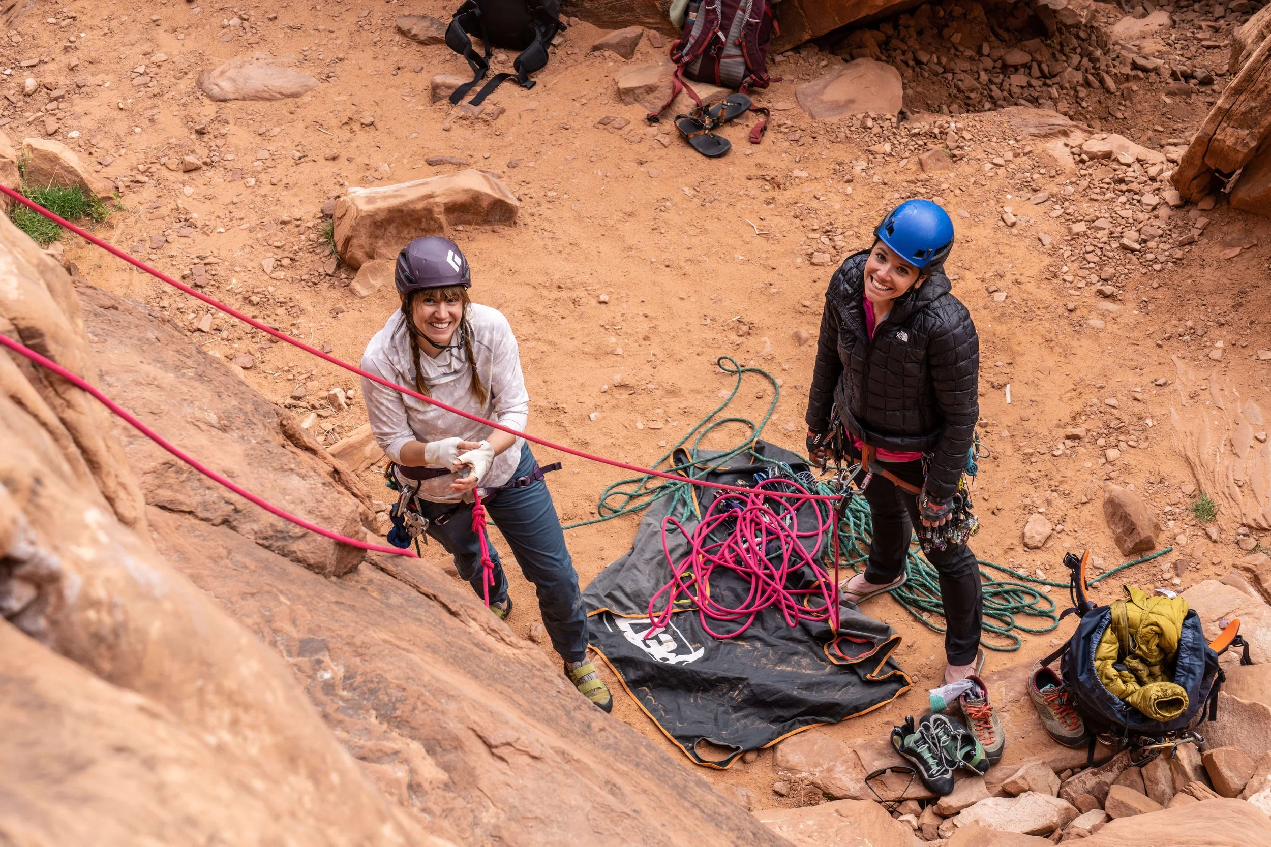 A guide and climber tie into the rope at the base of the cliff in Moab during a Gym to Crag climbing course.