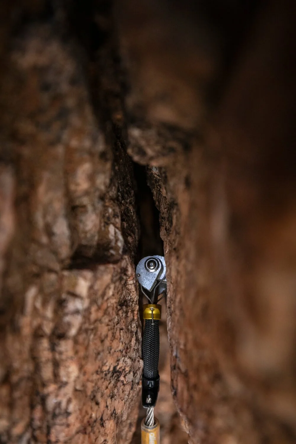 A spring loaded camming device is placed in a crack in the rock during an introduction to trad climbing course.